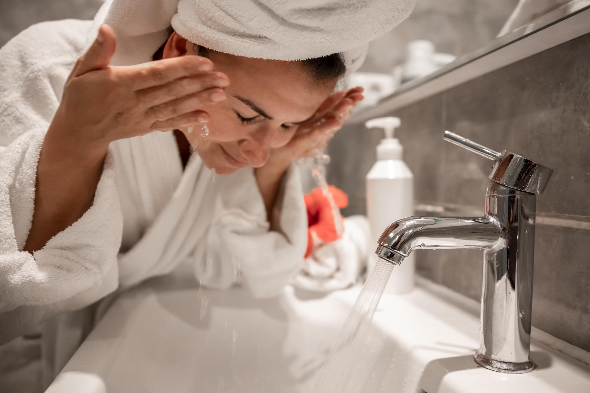 Mujer lavándose el rostro con agua de grifo. | Foto: Freepik
