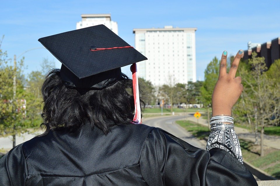 Recién graduada haciendo gesto de victoria con su mano. | Imagen: Max Pixel