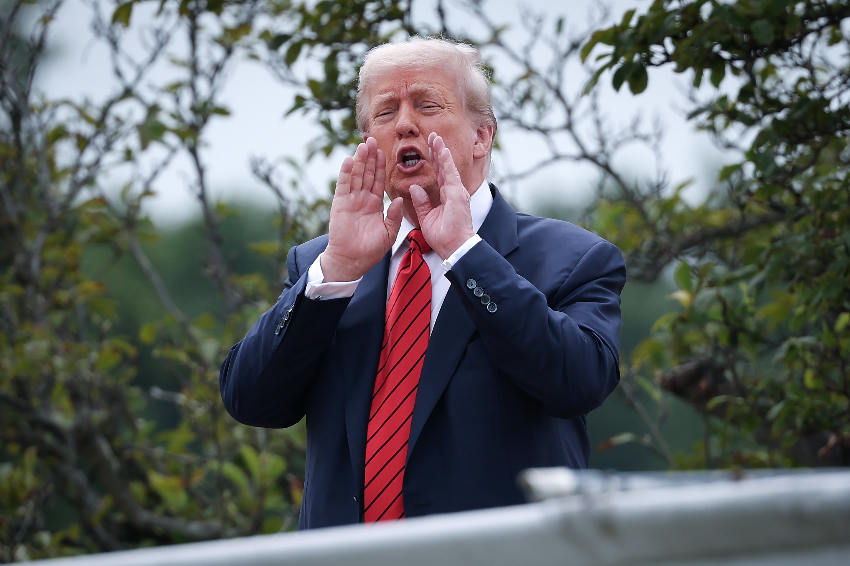 El presidente Donald Trump junta las manos y grita a los periodistas desde el techo del ala oeste de la Casa Blanca en Washington, D.C., respondiendo a las preguntas con un animado despliegue.