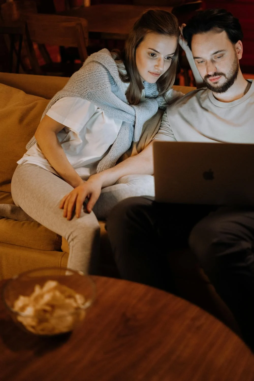 Una pareja feliz viendo una película en su sofá ⏐ Fuente: Pexels