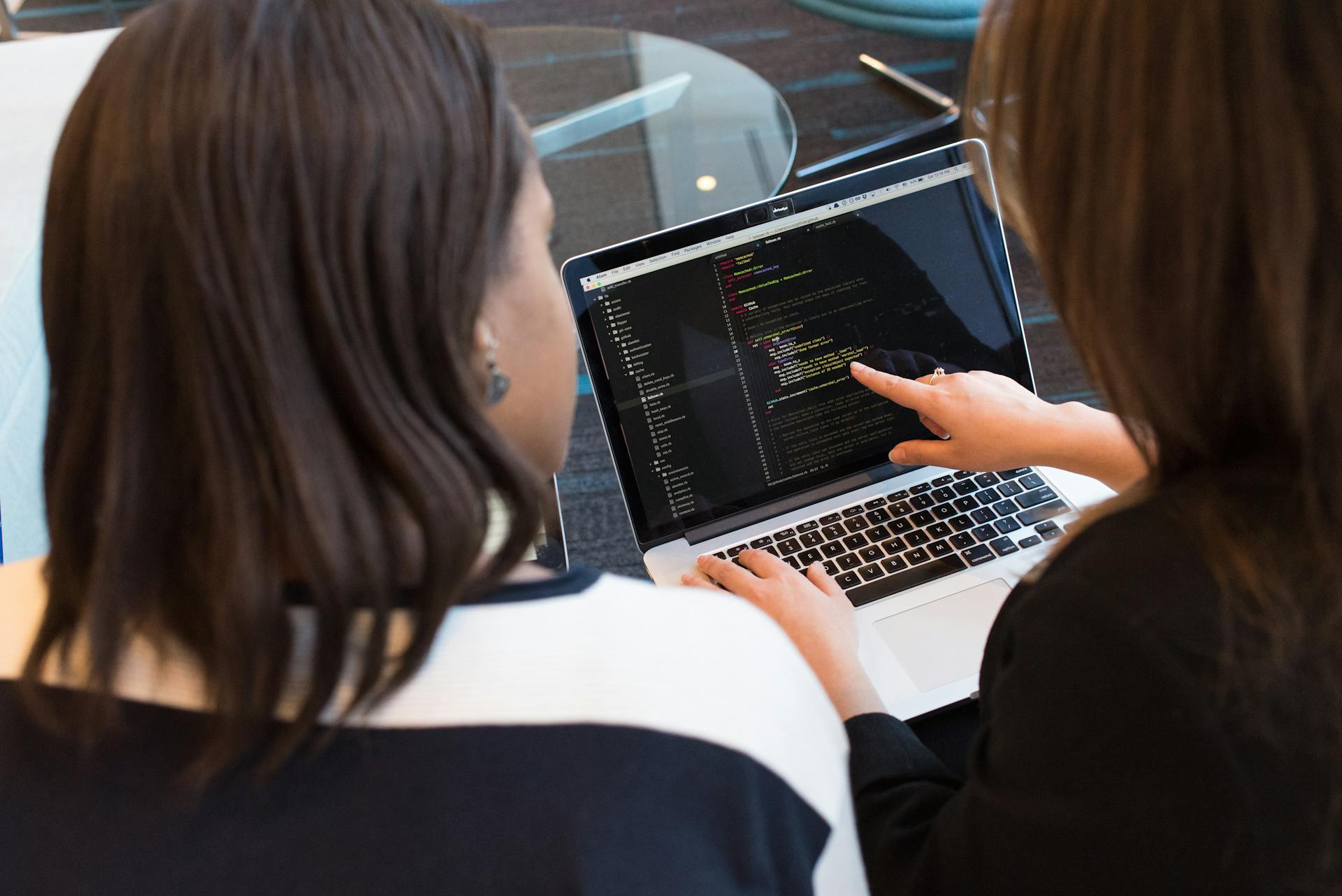 Dos mujeres mirando un código en la pantalla de un portátil | Fuente: Pexels