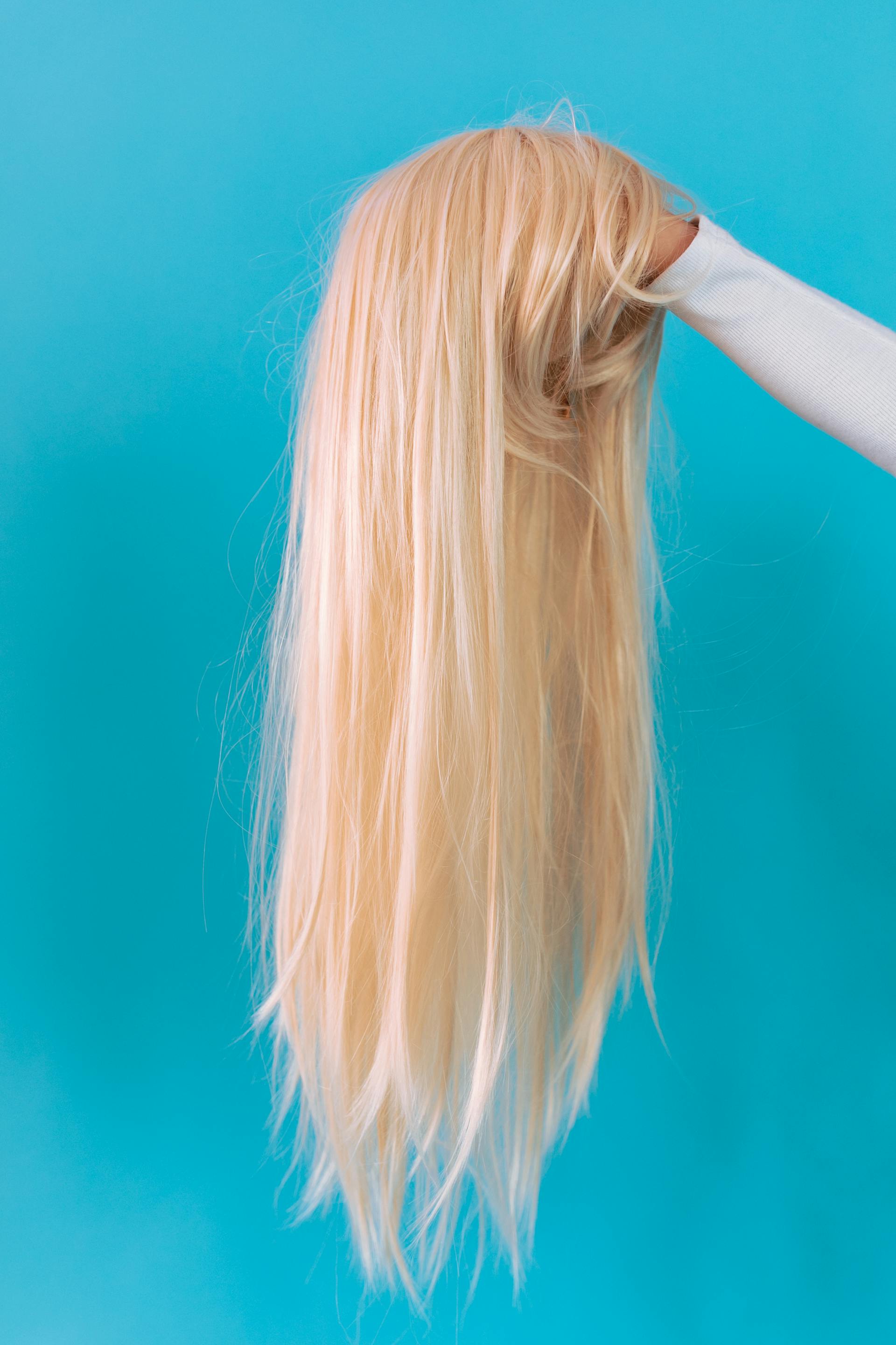 Mujer sujetando una peluca rubia | Fuente: Pexels