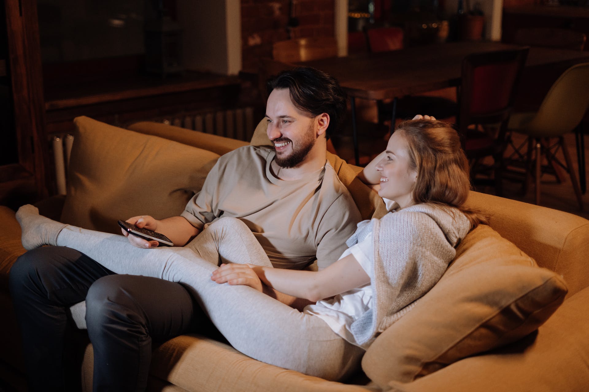 Una pareja abrazada mientras ve la tele en casa | Foto: Pexels