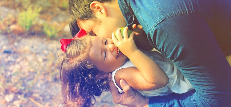 Padre besando a su pequeña hija sonriente. | Foto: Pixabay