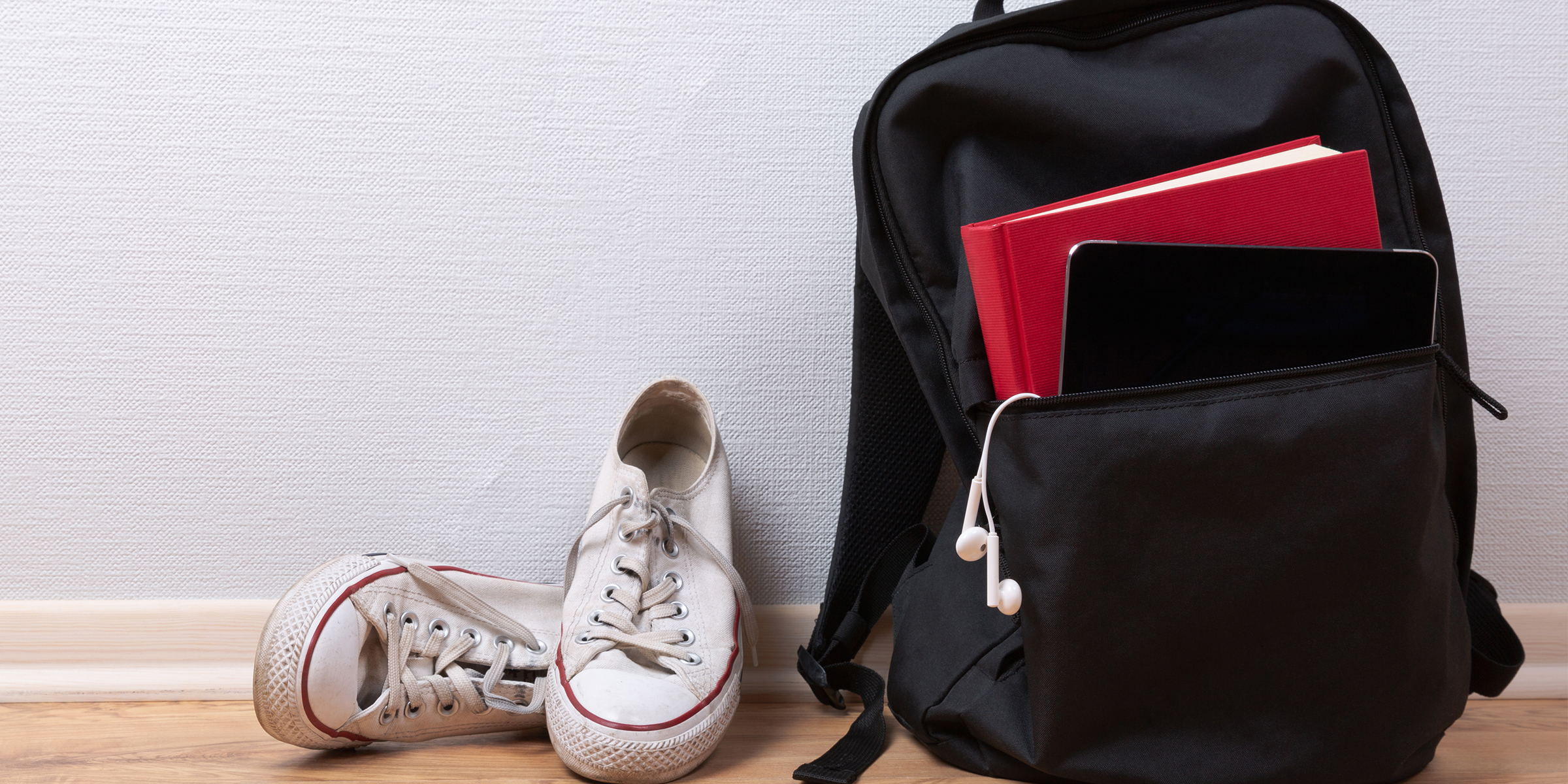 Una mochila negra junto a unas zapatillas blancas | Fuente: Shutterstock