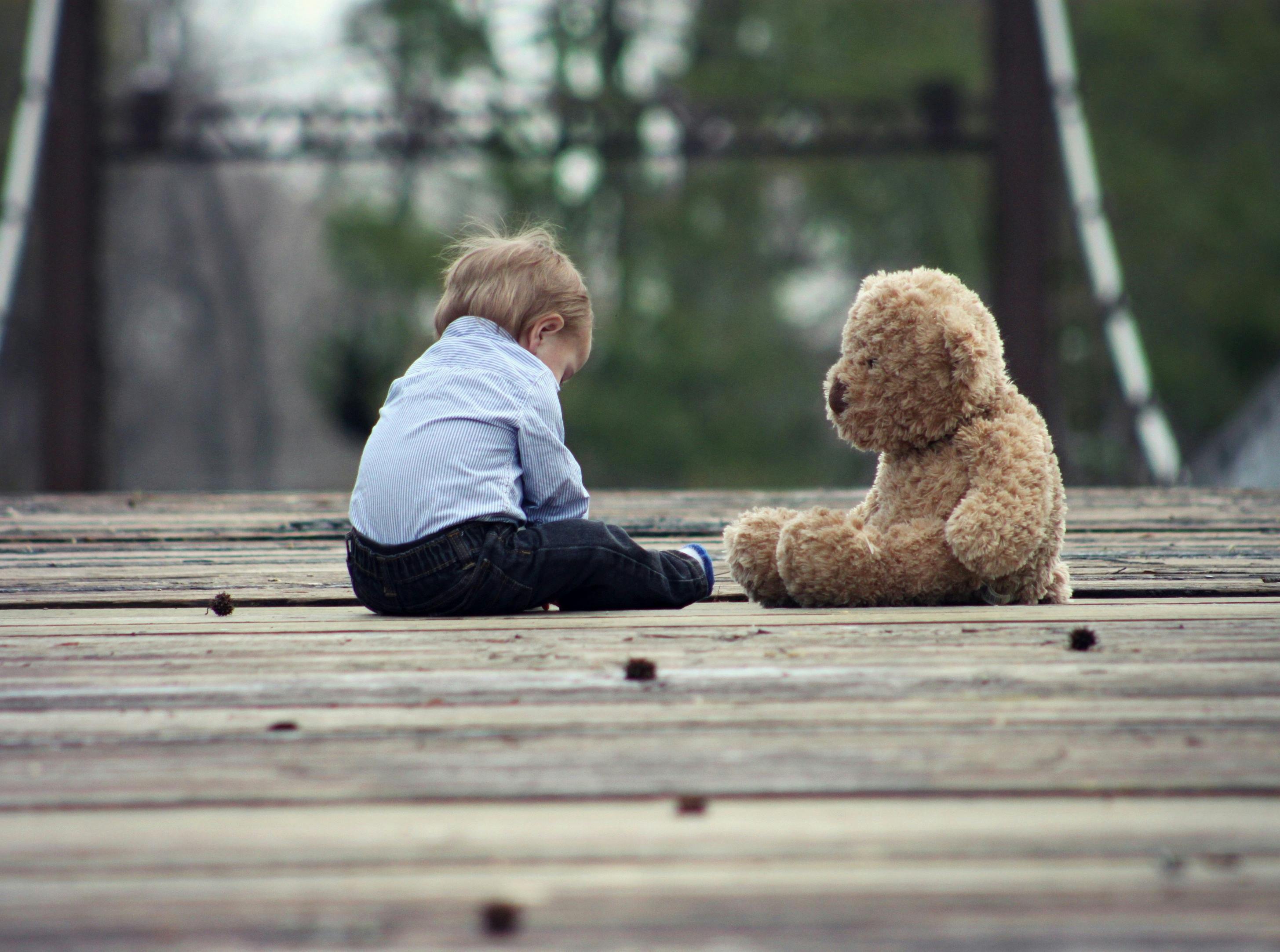 Un niño triste sentado junto a un oso de peluche | Fuente: Pexels