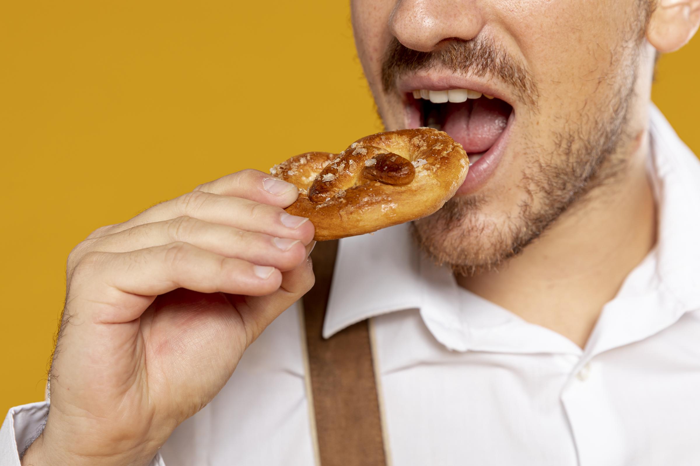 Primer plano de un hombre comiendo un pretzel | Fuente: Freepik