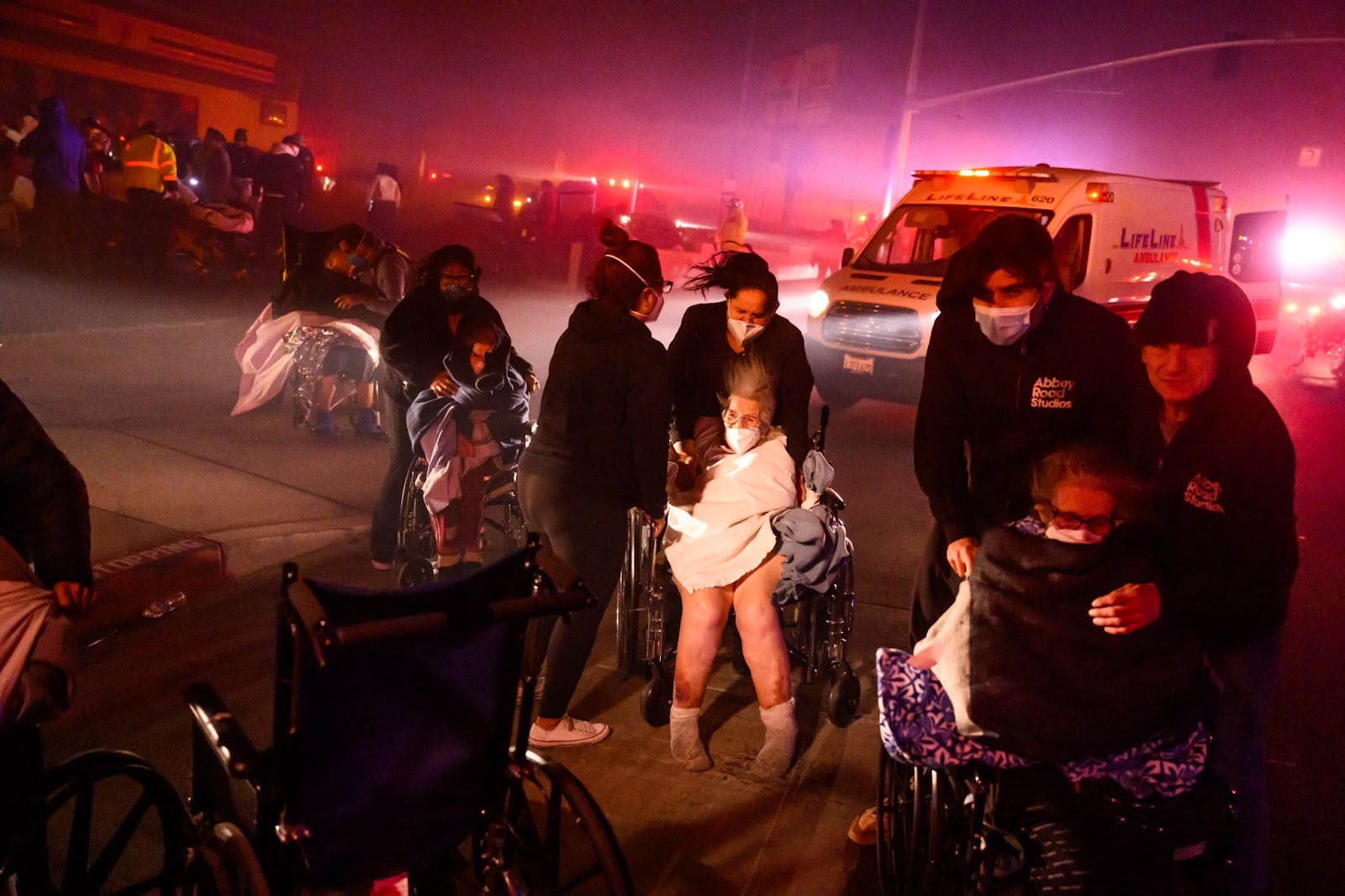 Pacientes ancianos son evacuados a vehículos de emergencia mientras las brasas y las llamas se acercan durante el incendio de Eaton en Pasadena, California, el 7 de enero de 2025. | Fuente: Getty Images