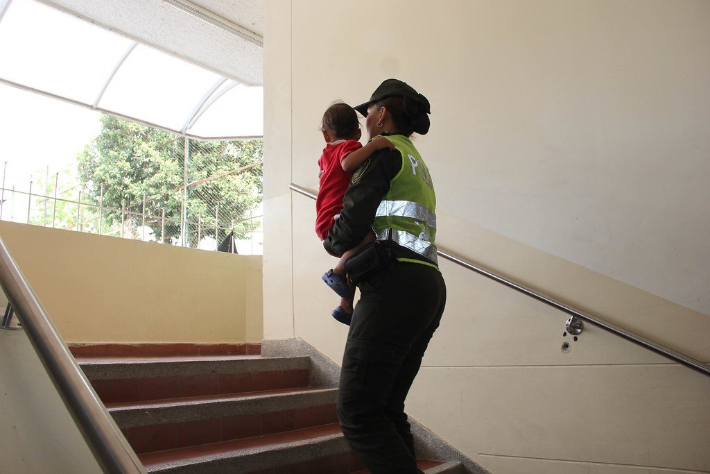 Policía sube escaleras con niño en sus brazos. | Foto Archivo: Flickr