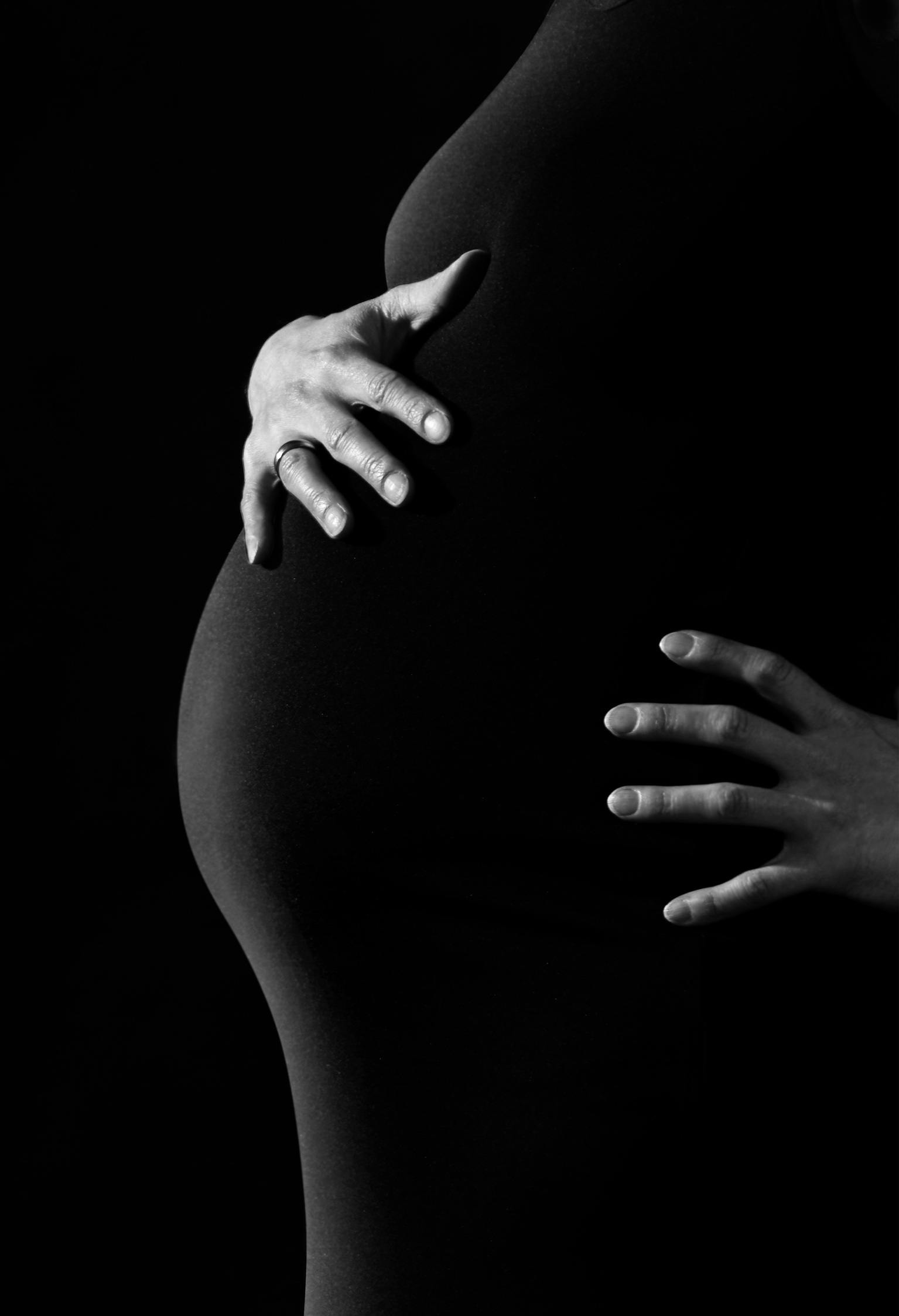 Foto en blanco y negro de una mujer sujetando su barriga de embarazada | Foto: Pexels