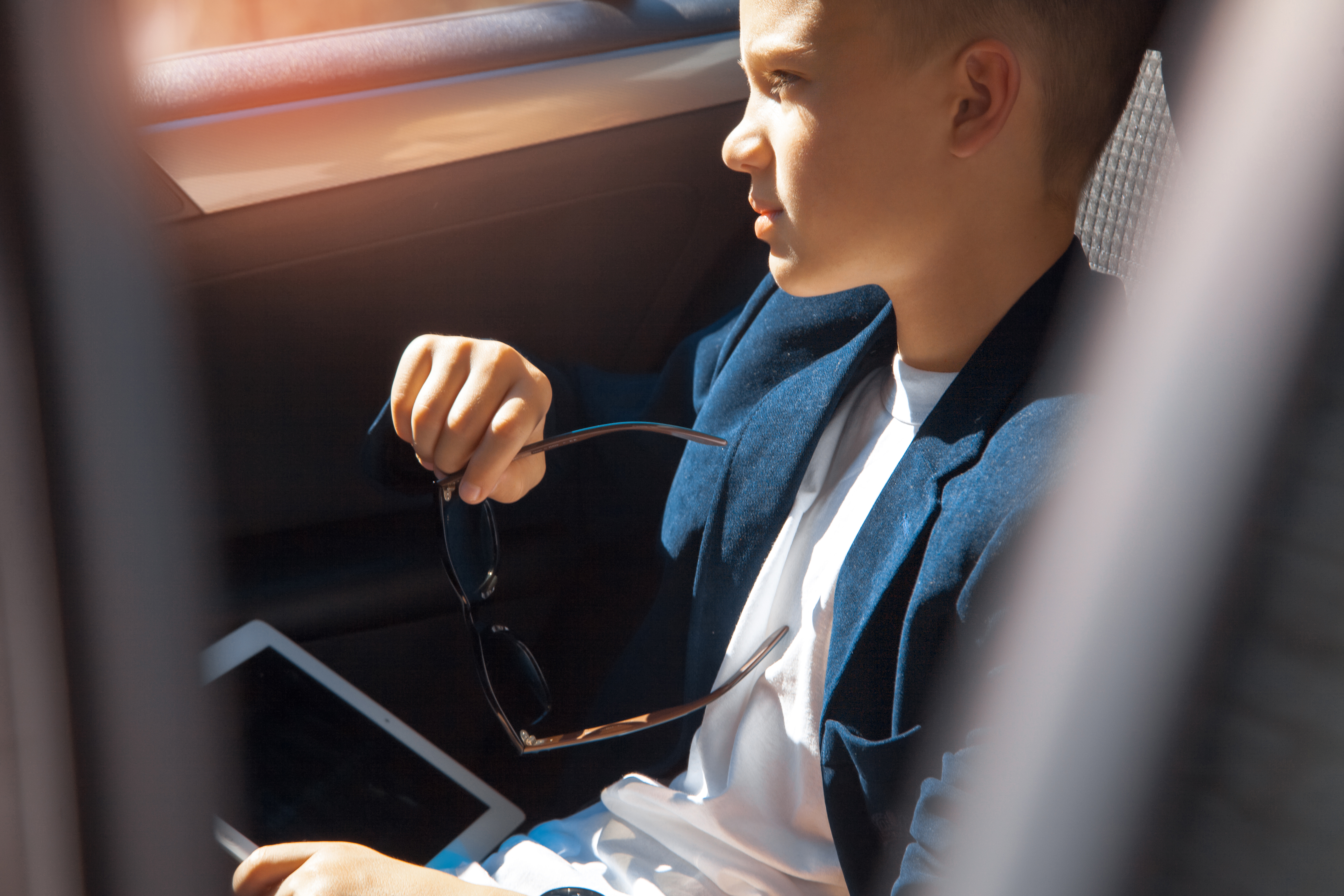 Joven rico sentado en el asiento trasero de un Automóvil. | Fuente: Shutterstock