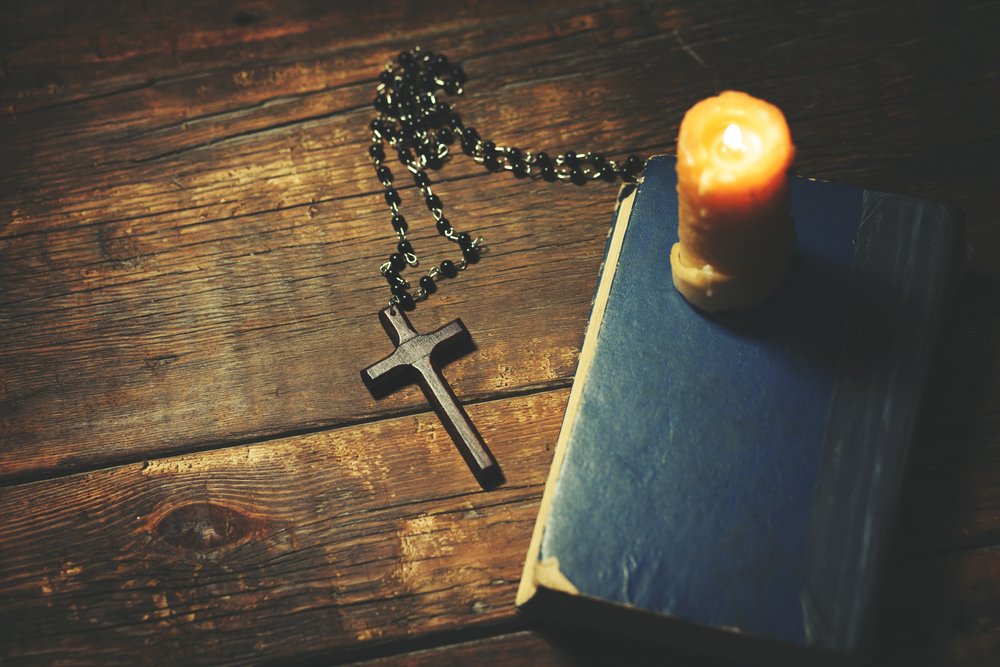 Biblia, rosario y una vela encendida.| Fuente: Shutterstock