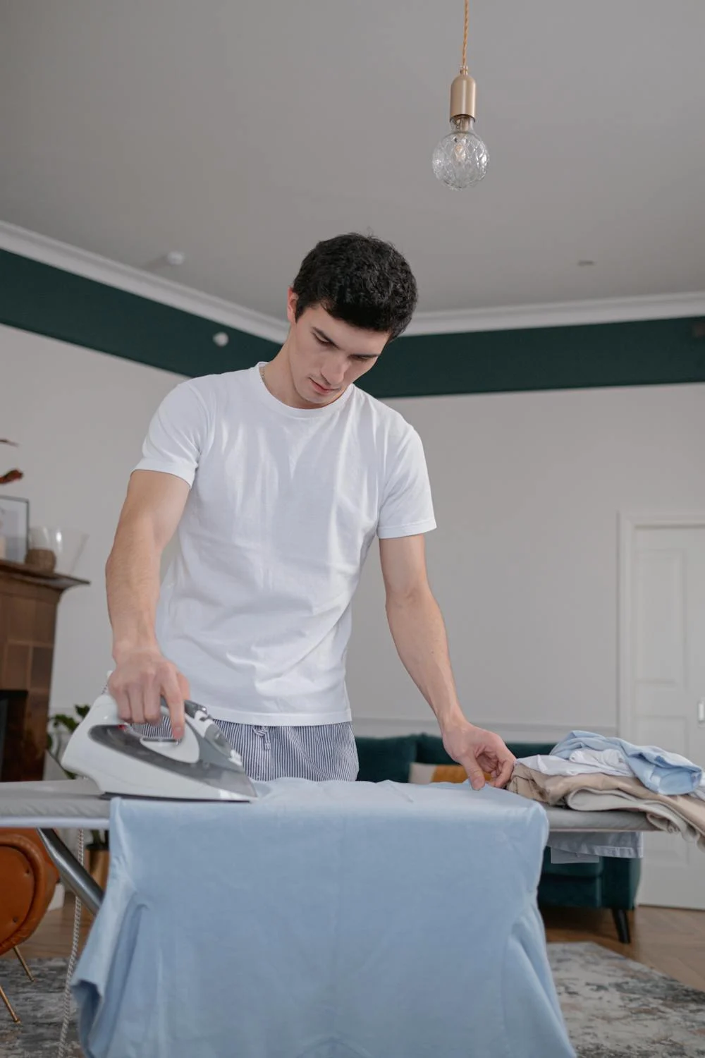 Un hombre planchando su camisa | Fuente: Pexels