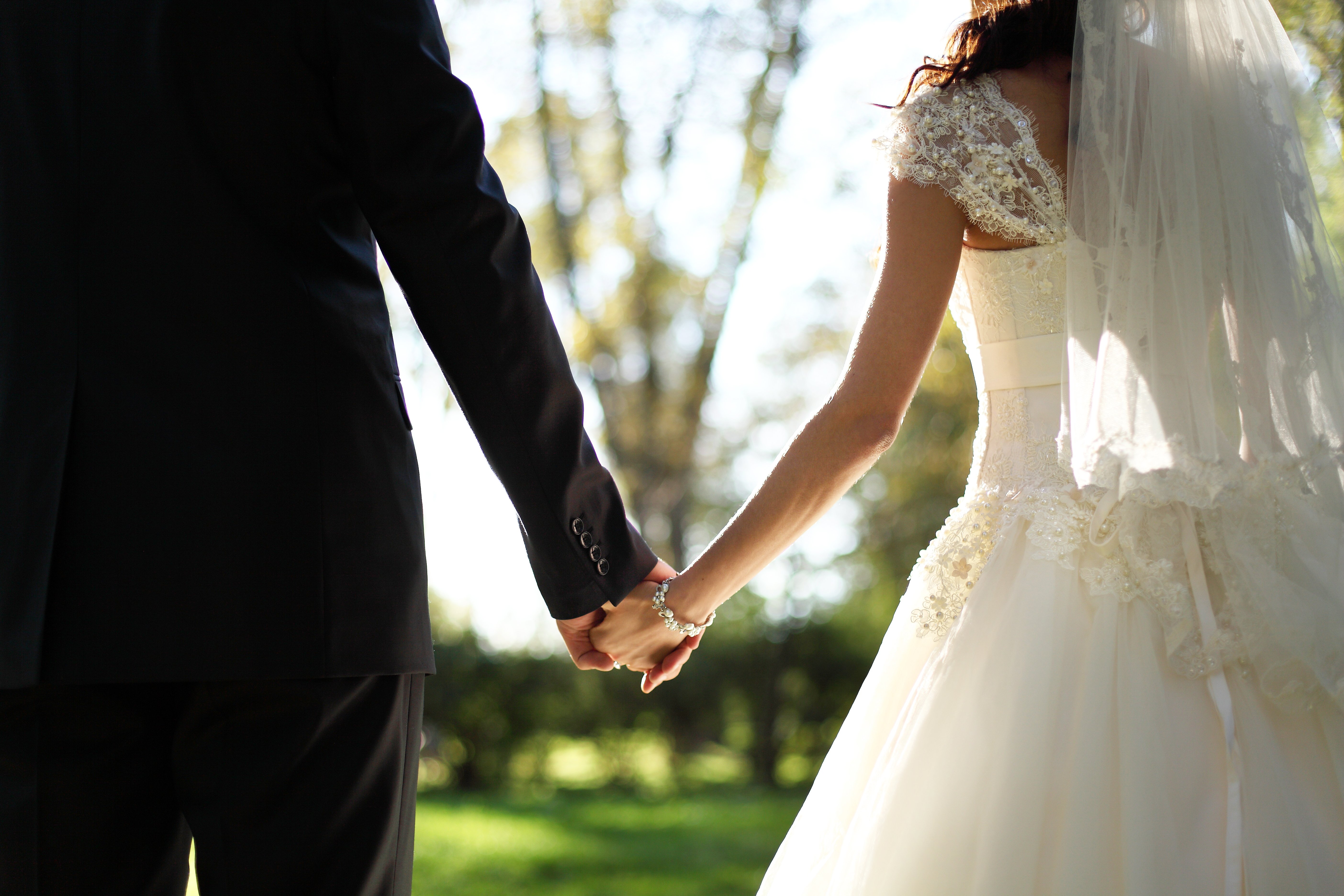 Pareja recién casada tomada de las manos. | Foto: Shutterstock