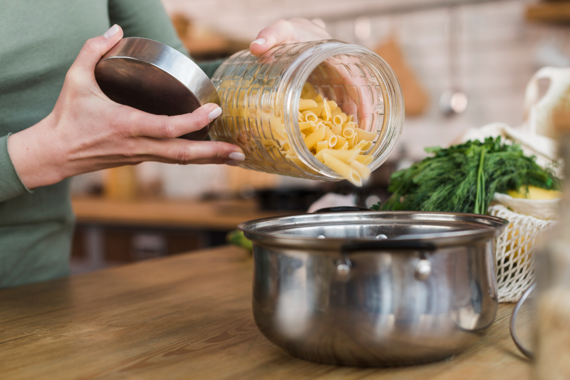 Una mujer vierte pasta cruda en una olla | Fuente: Freepik