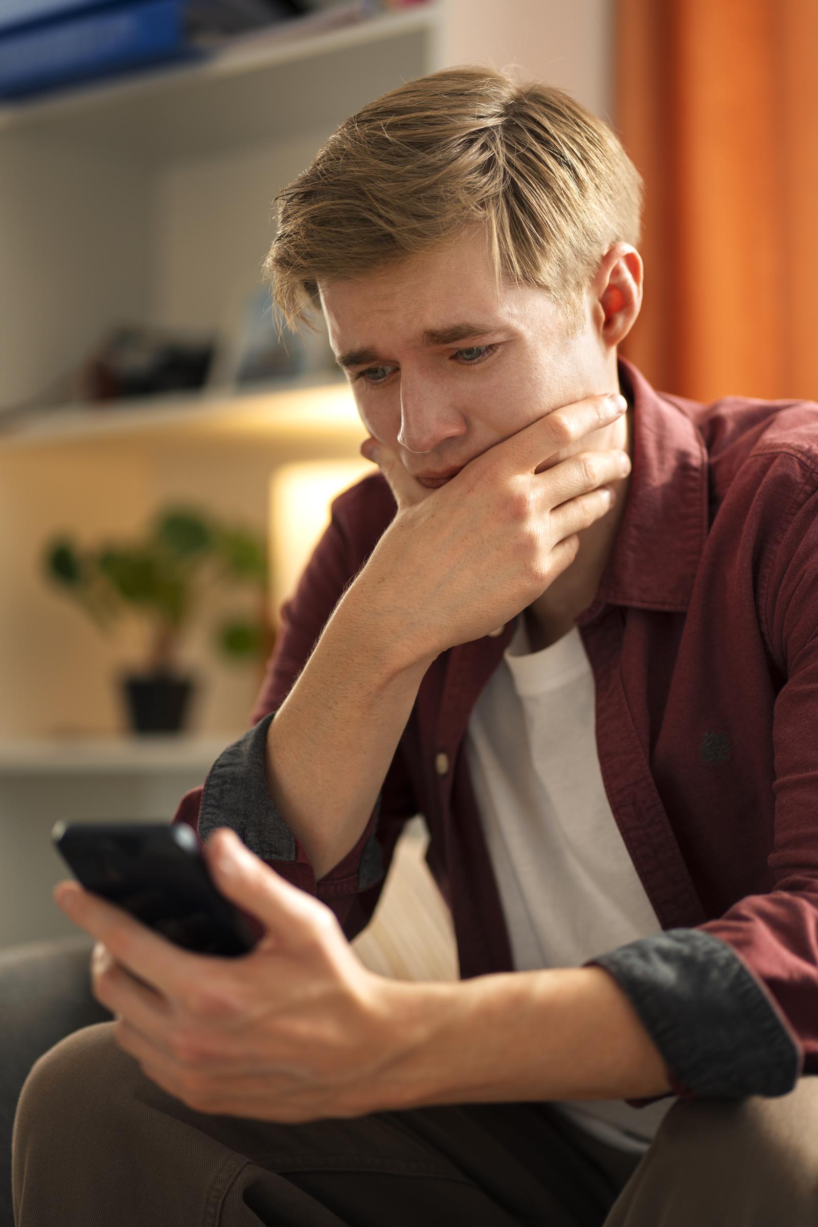 Un hombre desconcertado mirando su teléfono | Fuente: Freepik