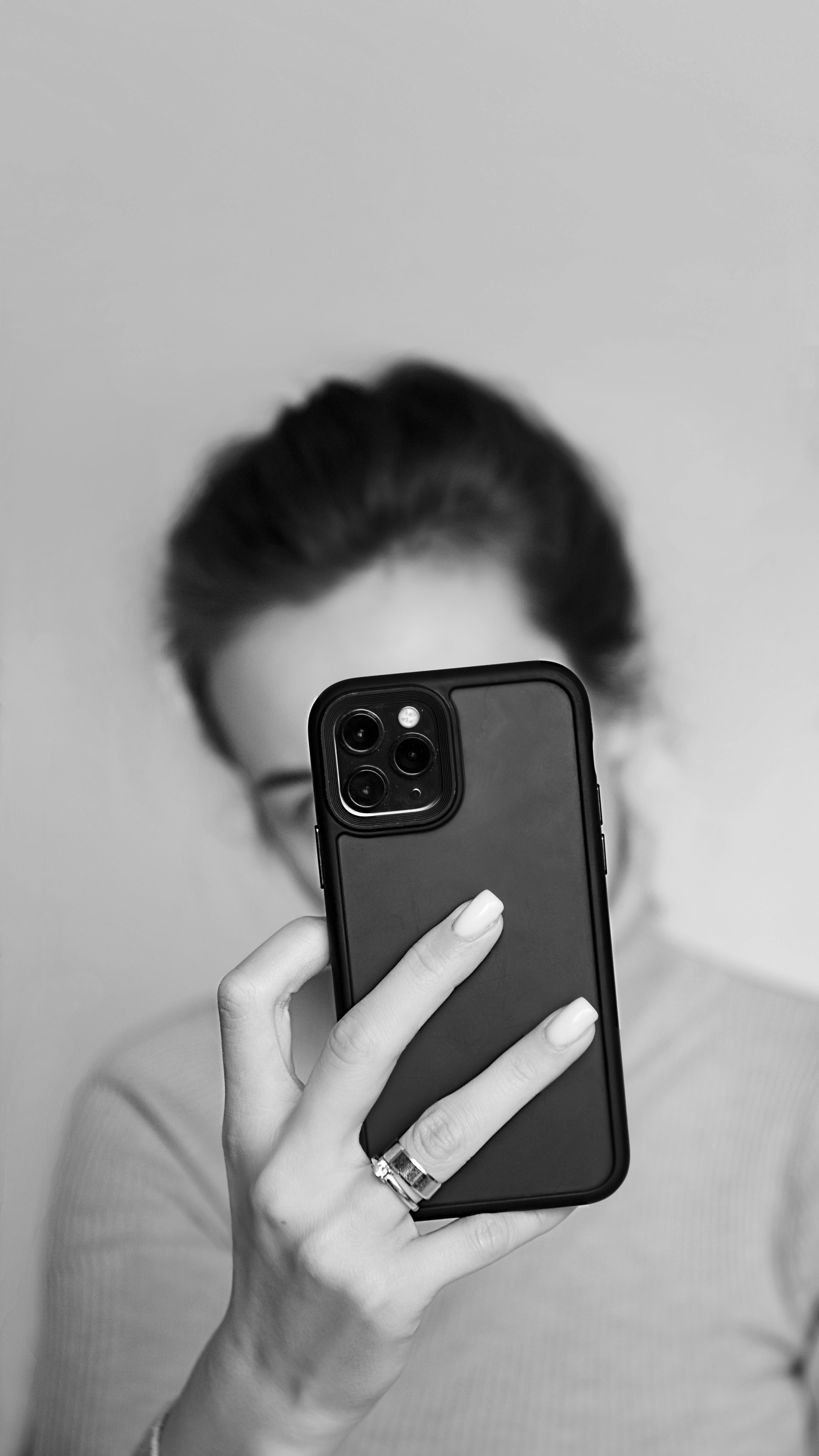 Una mujer oculta su rostro con su teléfono | Fuente: Pexels