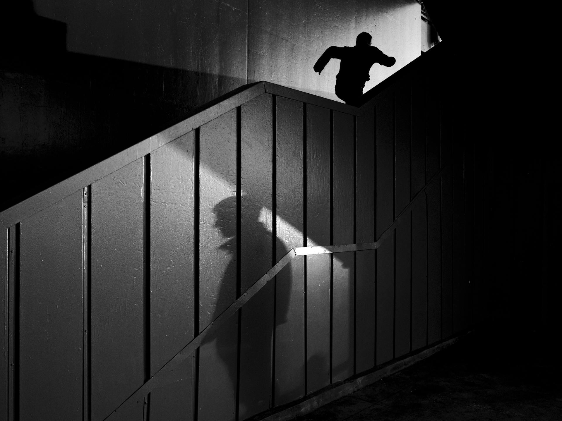 Silueta de la sombra de un hombre y otro corriendo escaleras arriba | Fuente: Pexels