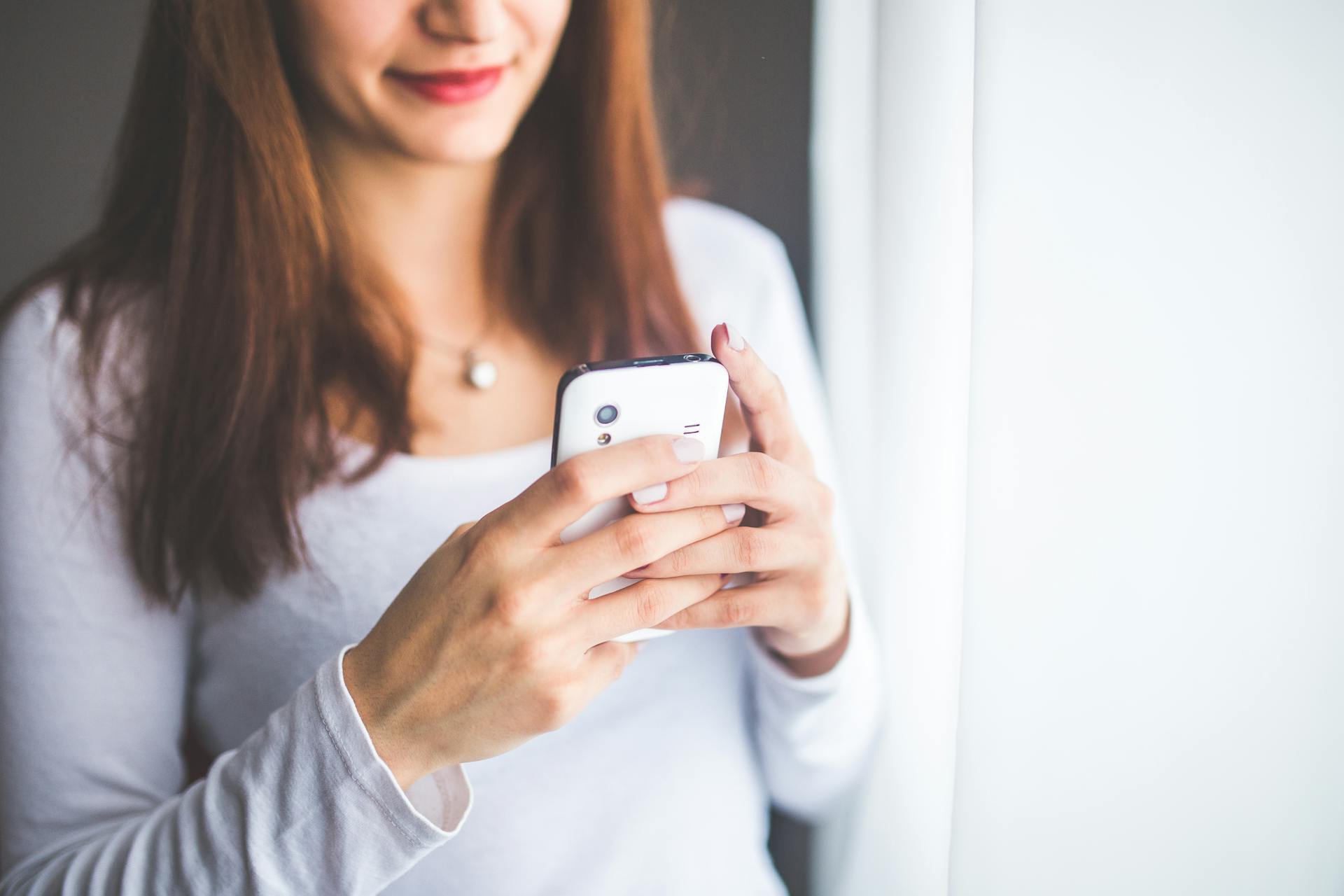 Una mujer sujetando un smartphone blanco | Fuente: Pexels