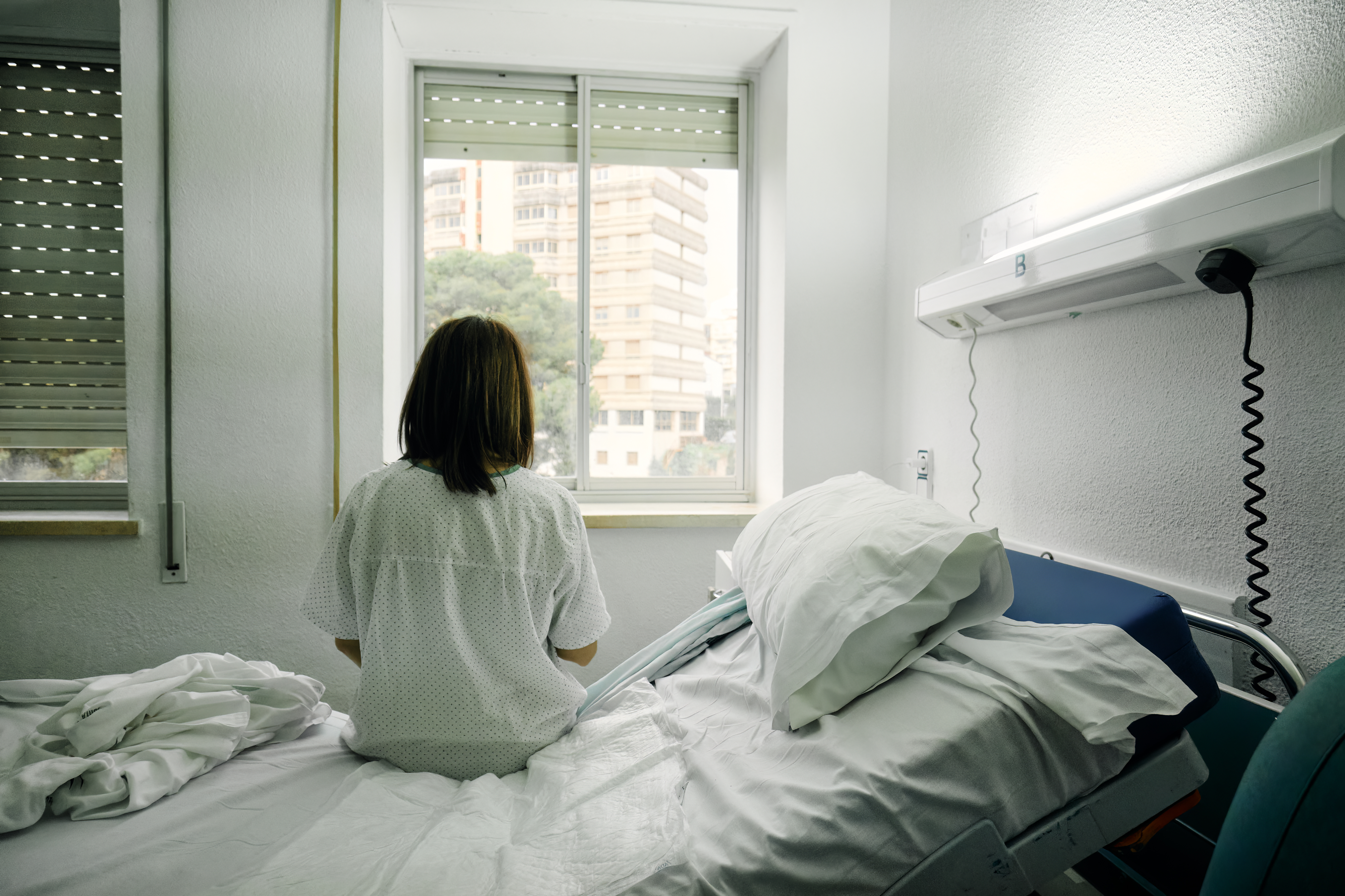 Vista posterior de una mujer sentada en una cama de hospital | Fuente: Getty Images