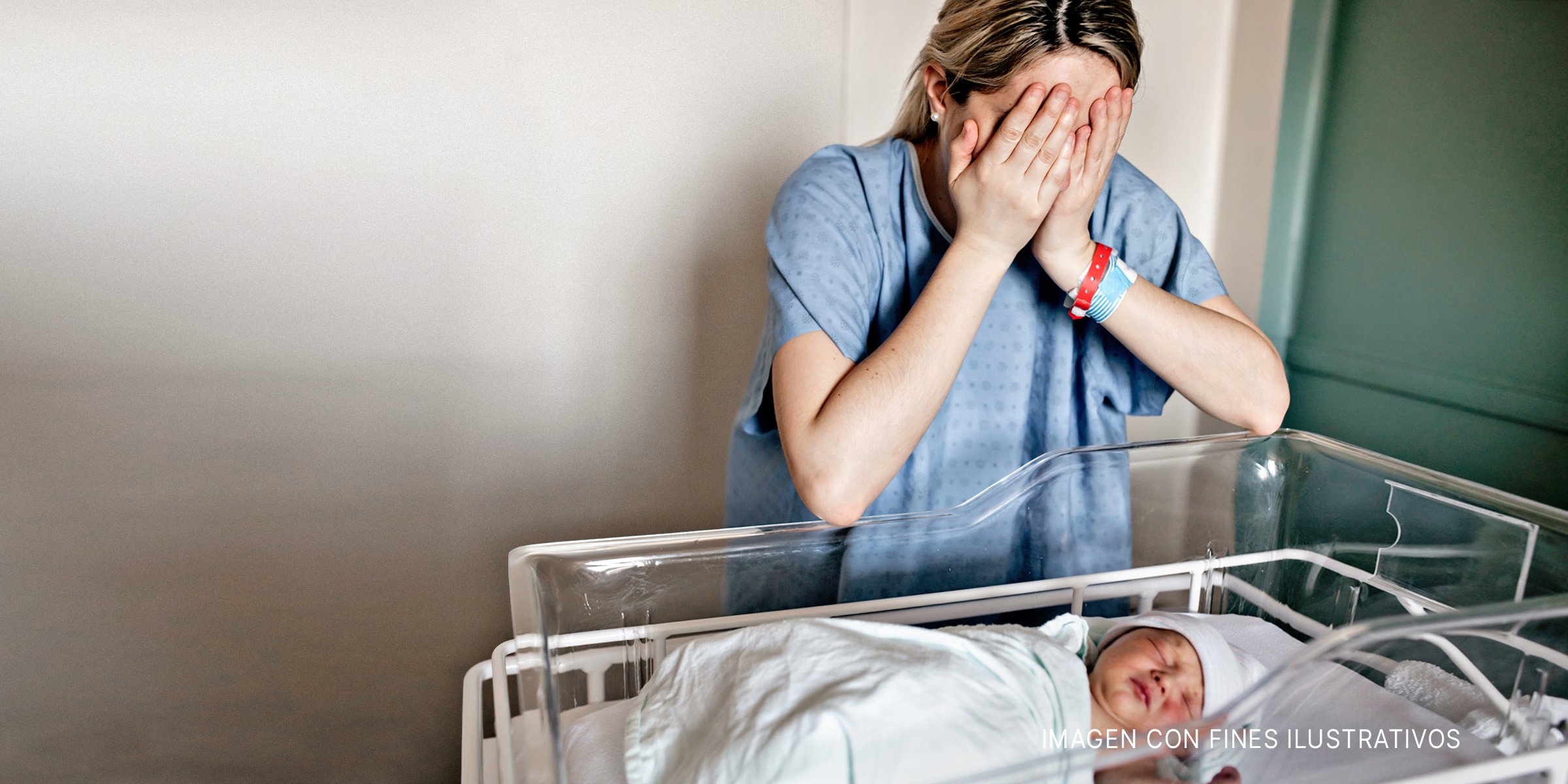 Madre llorando cerca del bebé recién nacido en la cuna | Foto: Shutterstock