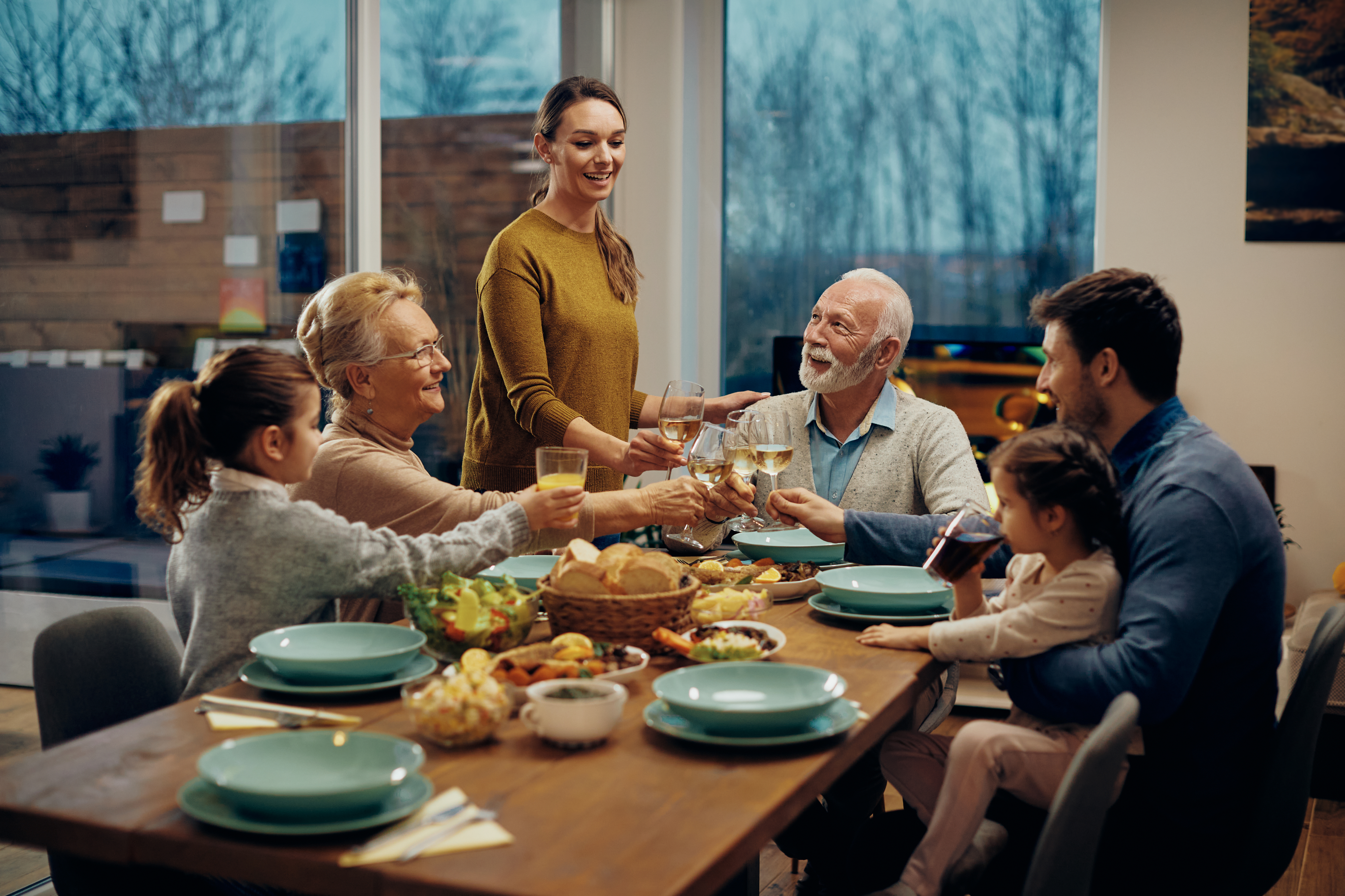 Una familia extendida feliz brindando mientras almuerzan juntos en un comedor. | Foto: Shutterstock