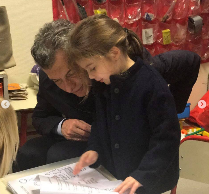 Inclinado sobre una mesa baja de guardería, Mauricio Macri acompaña con atención a Antonia mientras ella hojea unas hojas de actividades escolares. La niña viste un abrigo azul marino de botones mientras su padre la observa de cerca con una sonrisa. | Fuente: Instagram/mauriciomacri