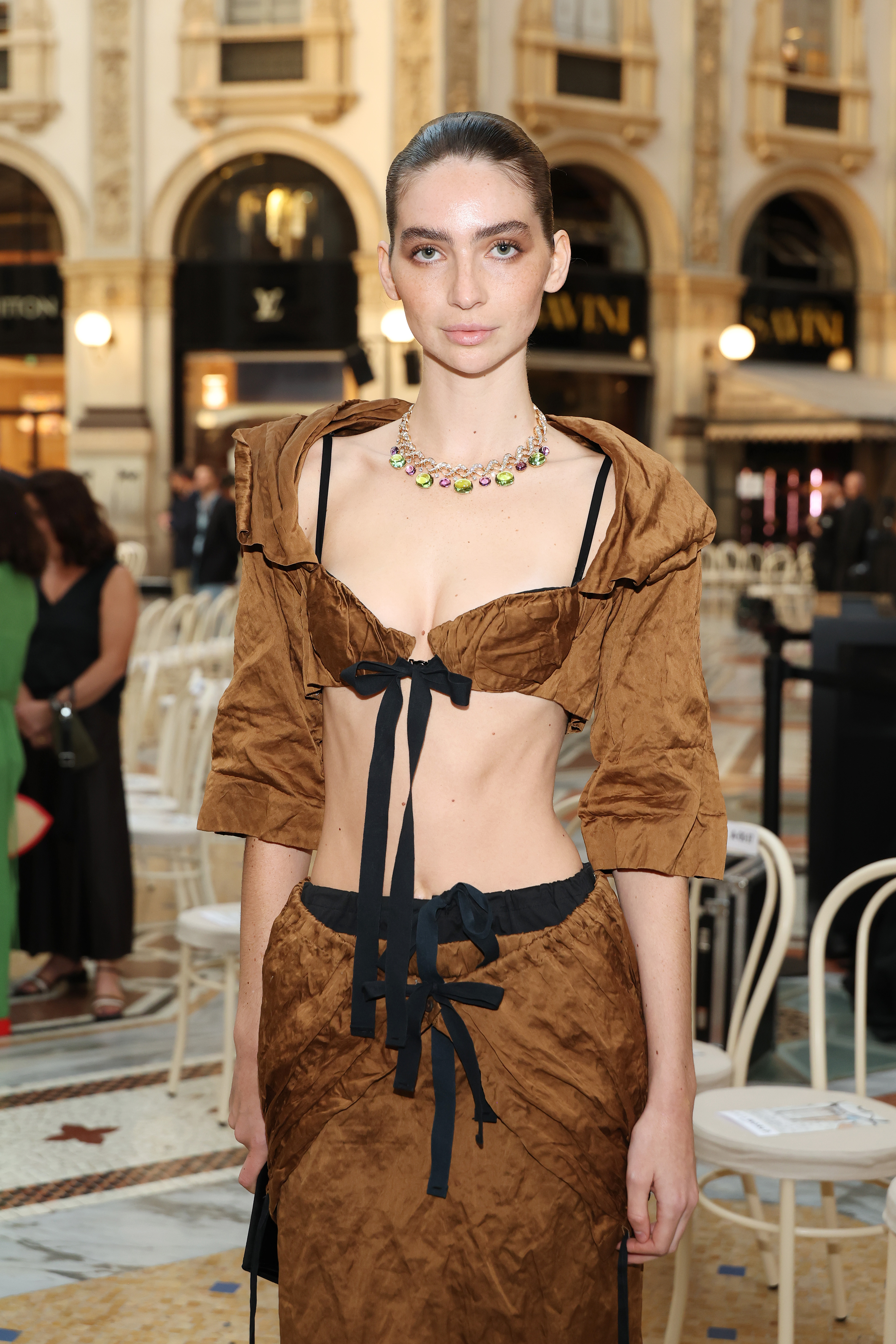 Walker posa para los fotógrafos dentro del recinto; el primer plano resalta su colorido collar de joyas, su escote pronunciado y su lazo negro. | Fuente: Getty Images