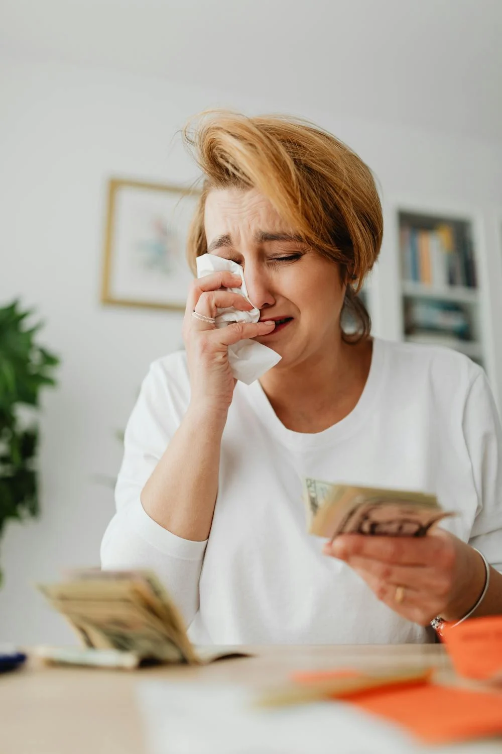 Una mujer llora mientras sostiene dinero | Fuente: Pexels