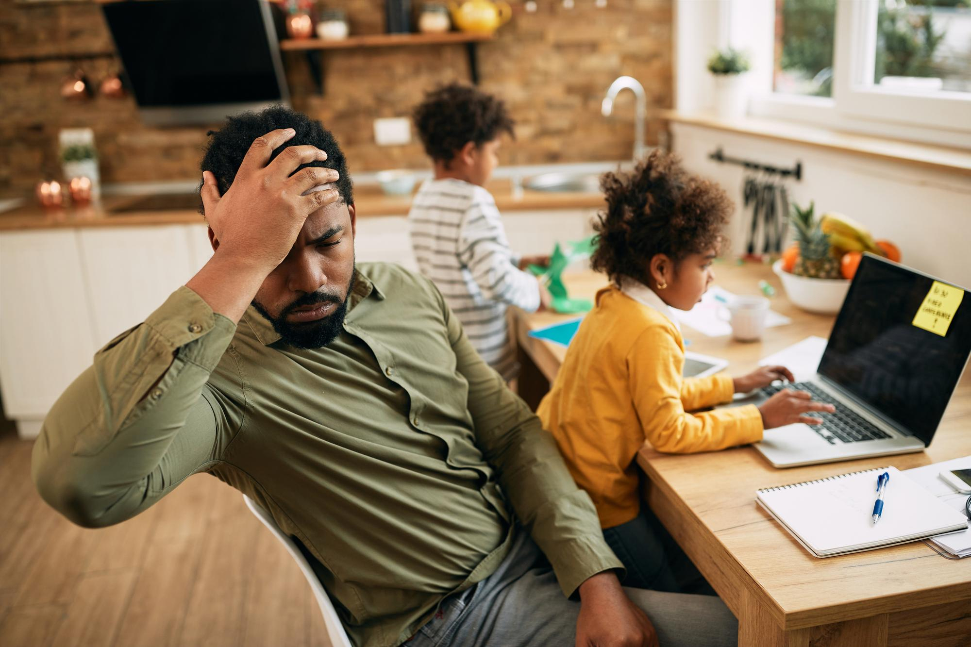 Un hombre estresado sentado con sus hijos | Fuente: Freepik