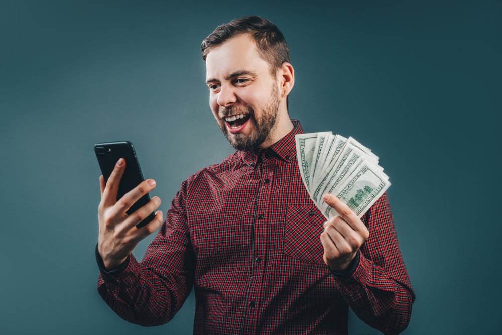  Retrato de medio cuerpo de hombre barbudo vestido informalmente sorprendido después de ganar la lotería en línea. I Foto: Shutterstock