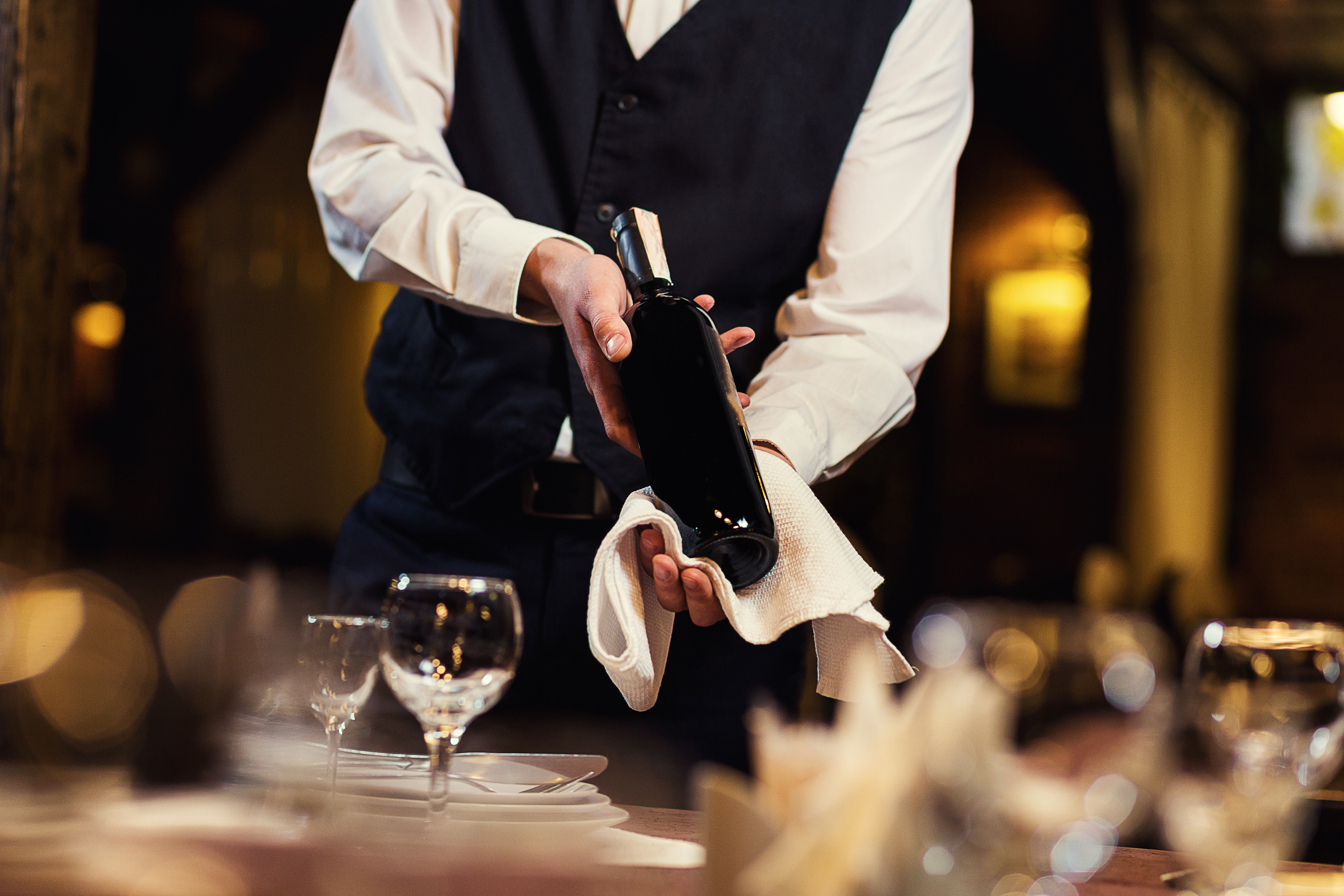 El camarero de uniforme con una toalla blanca. | Fuente: Shutterstock