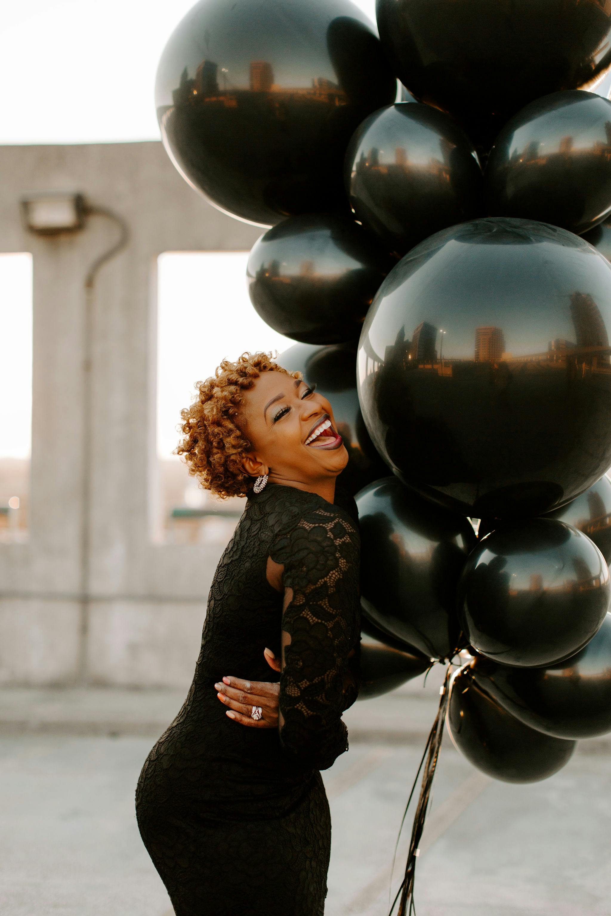 Una mujer riendo mientras sostiene globos | Fuente: Pexels