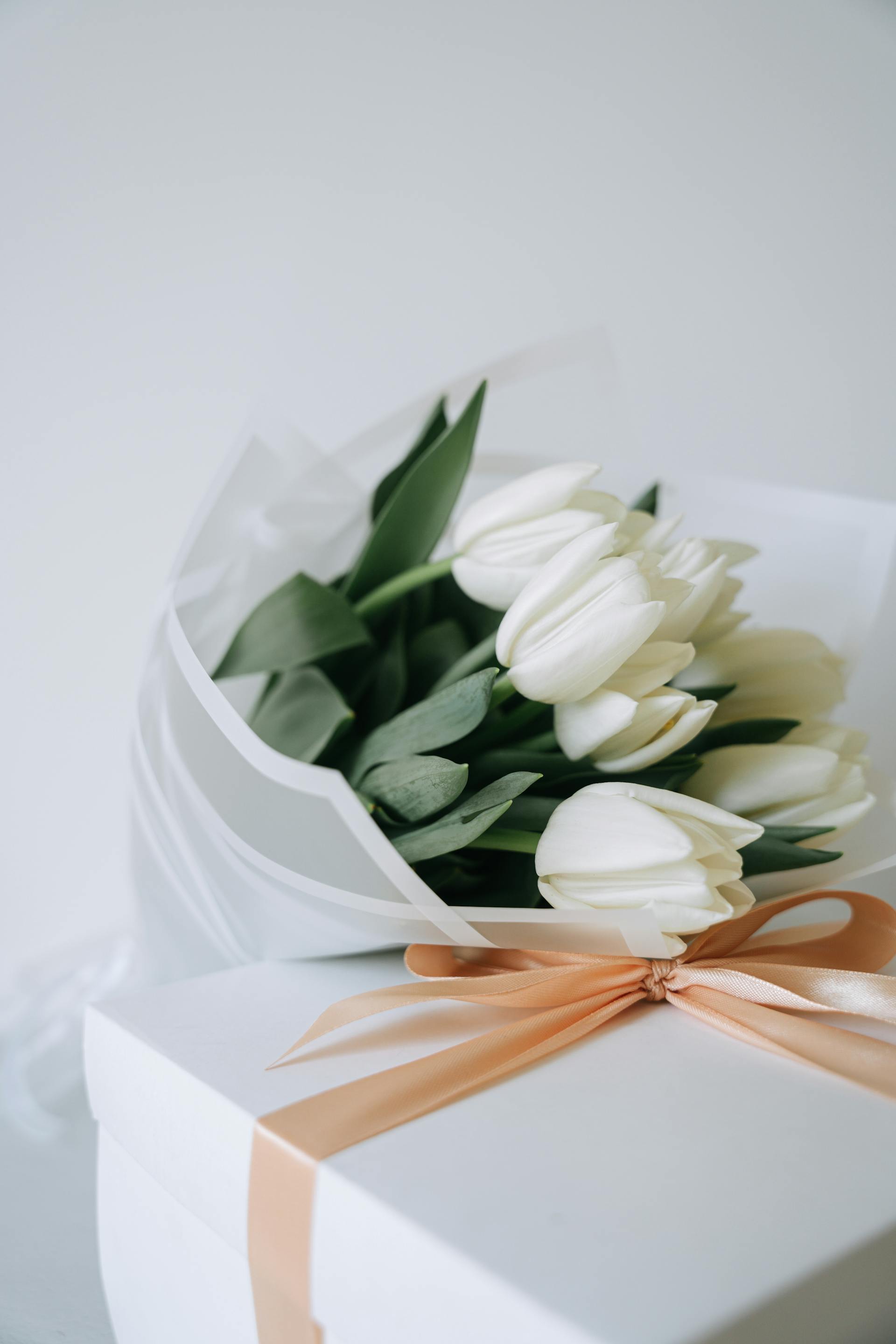 Un ramo de tulipanes blancos y una caja de regalo | Foto: Pexels