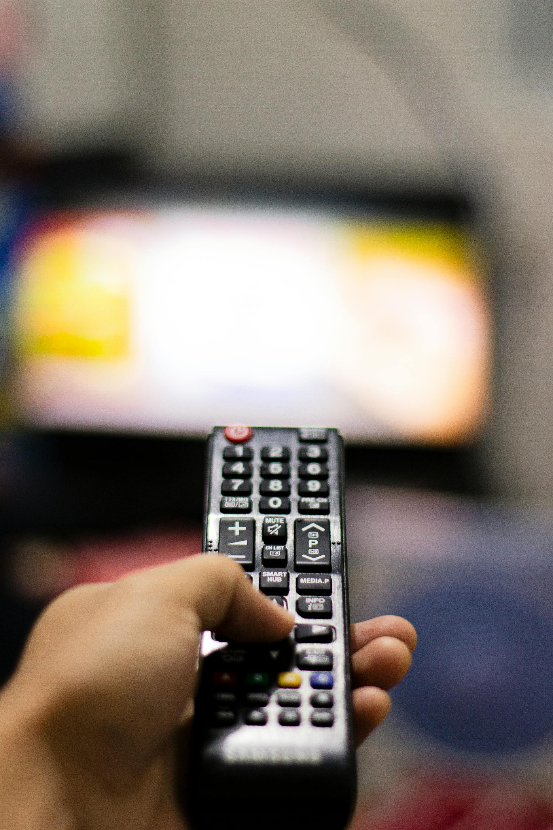 Una persona sujetando el mando a distancia de un televisor | Fuente: Pexels
