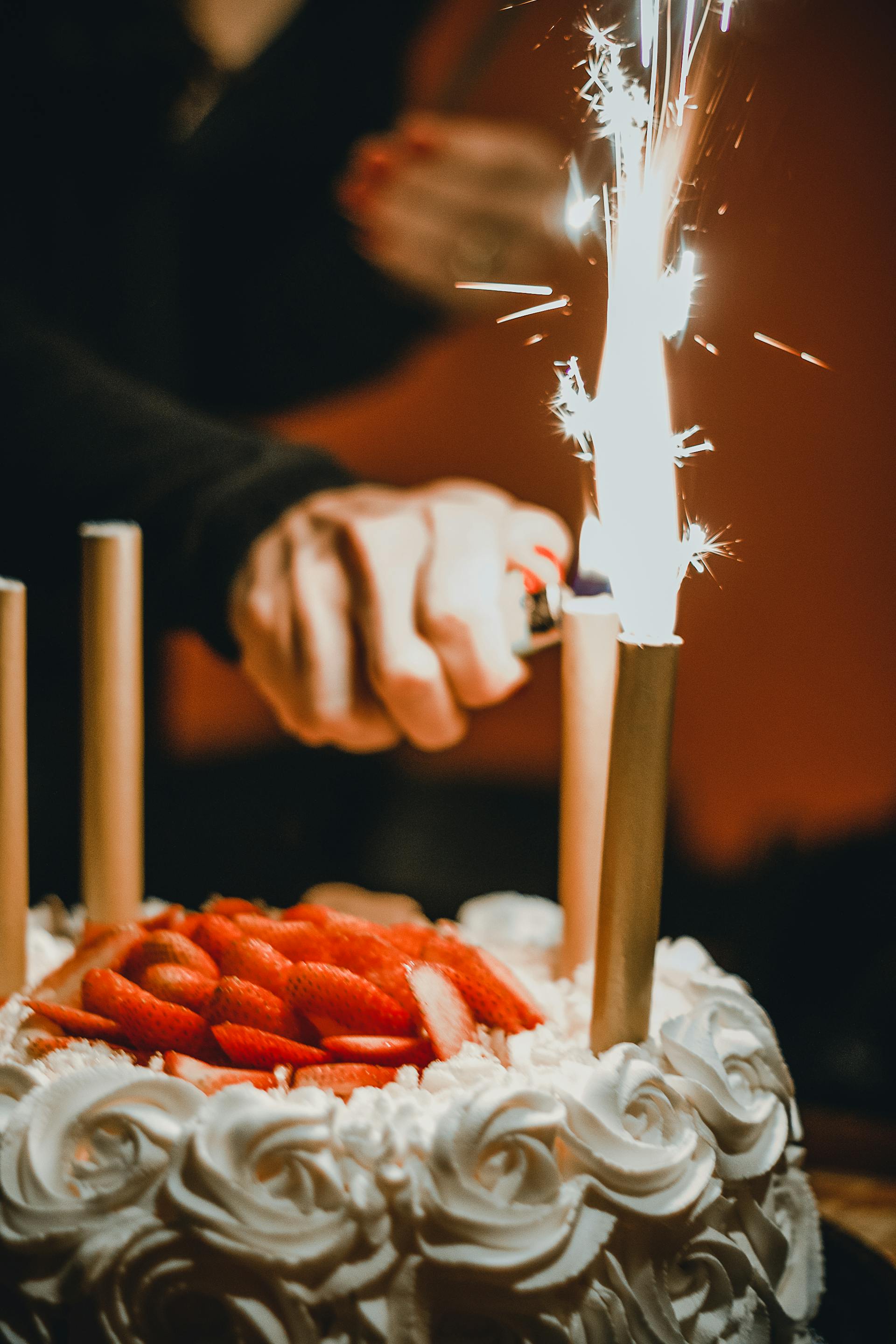 Persona encendiendo bengalas en un pastel | Foto: Pexels
