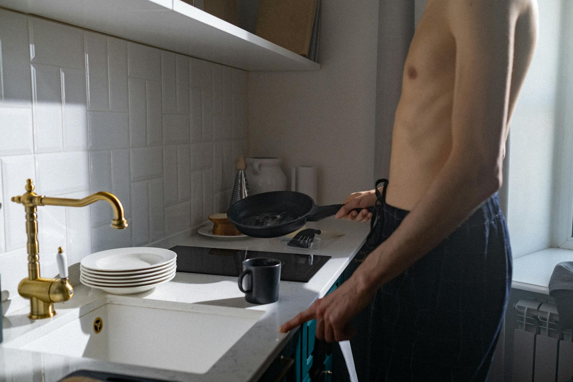 Un hombre sin camiseta cerca de un fregadero | Fuente: Pexels