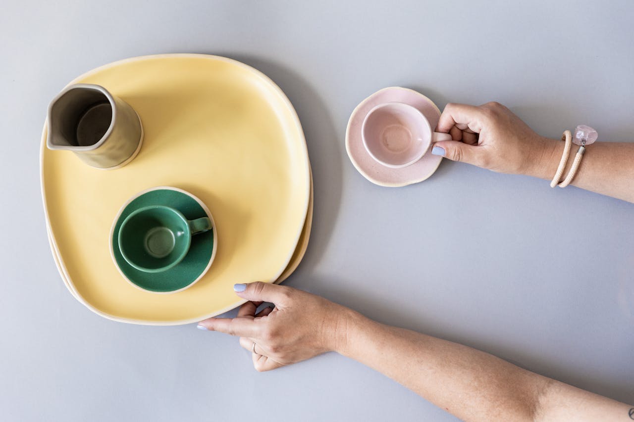 Una mujer recogiendo platos y tazas vacíos | Fuente: Pexels