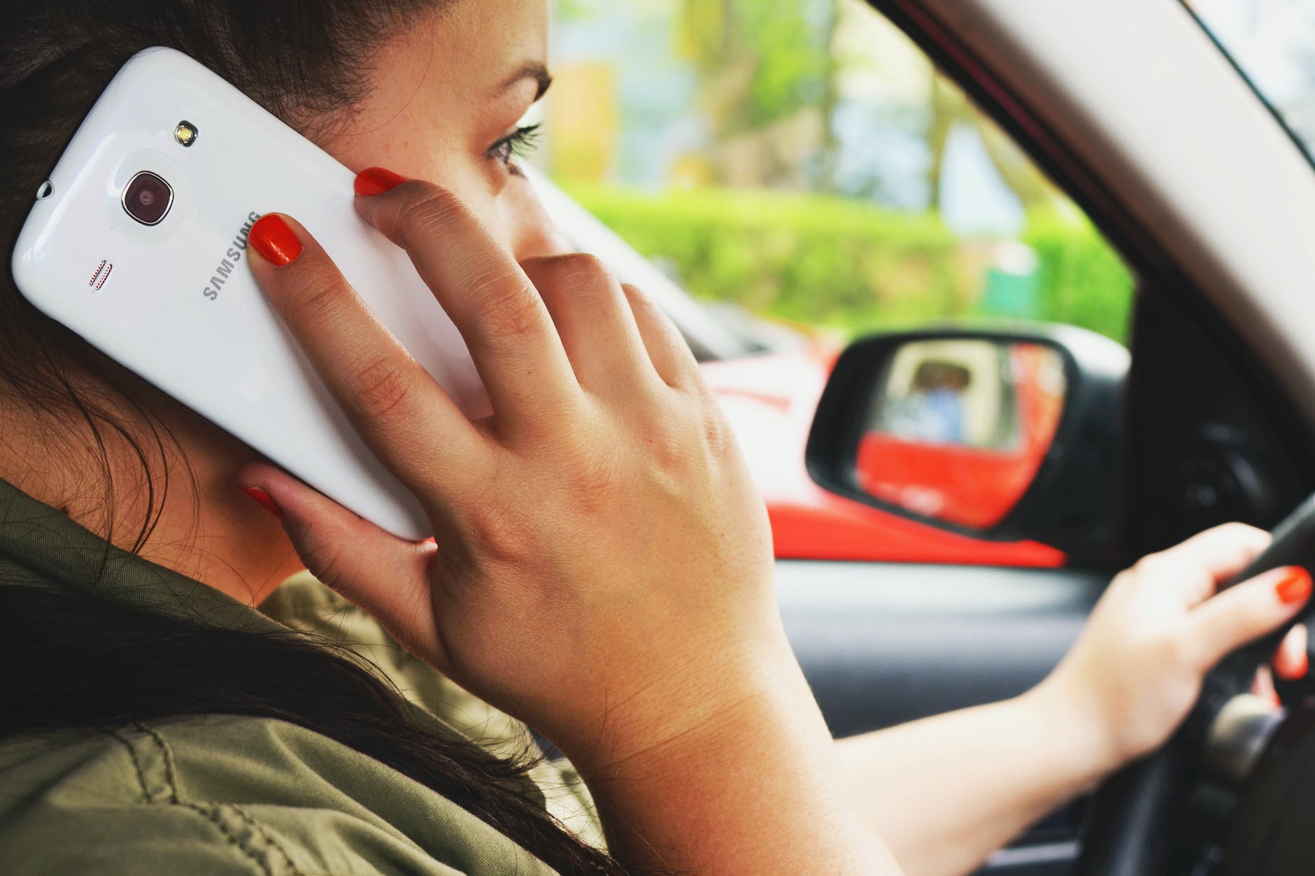 Una mujer conduciendo un automóvil mientras habla a través de un teléfono celular. | Foto: Pexels
