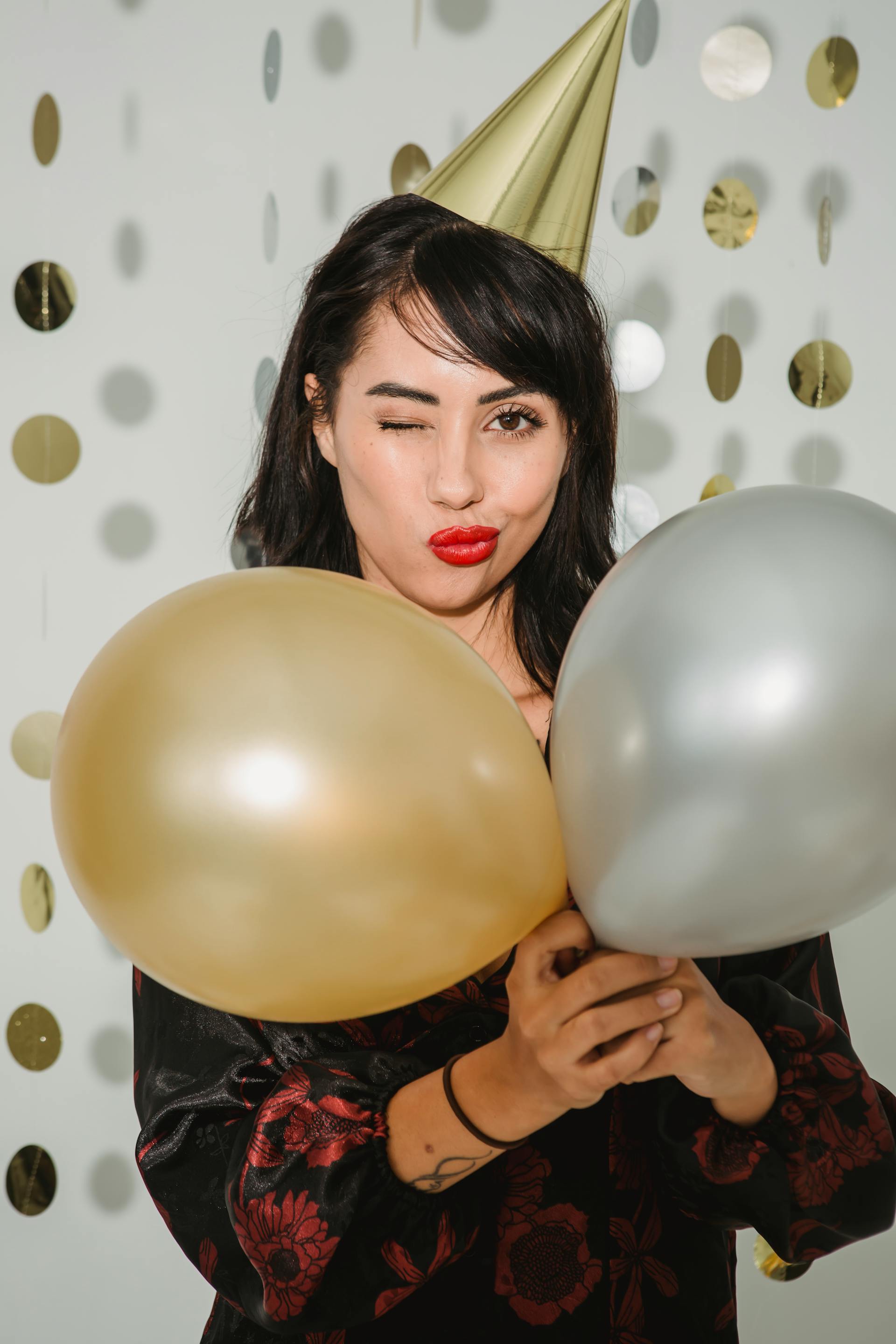 Una mujer en una fiesta sujetando globos | Fuente: Pexels