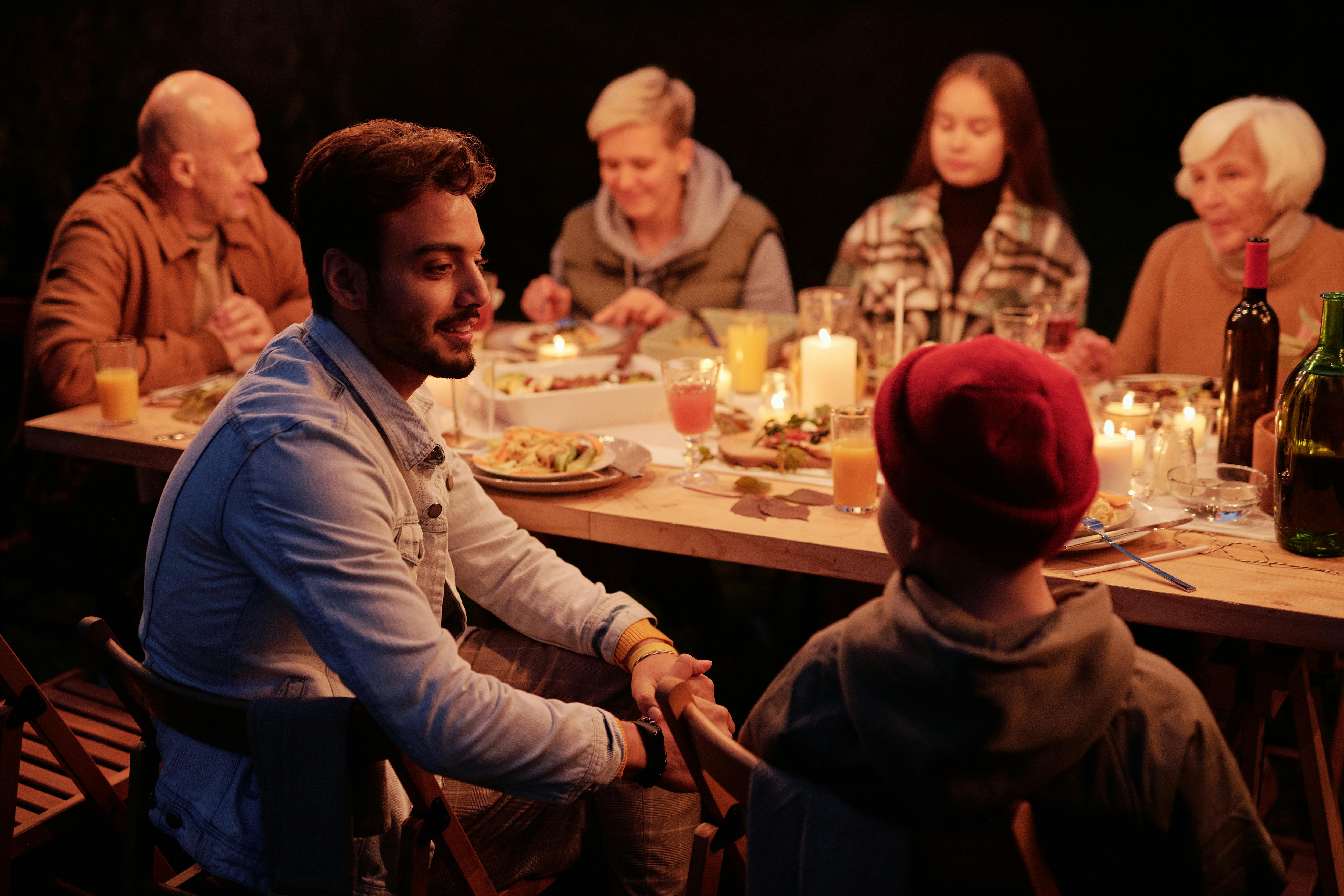 Gente reunida cenando en un jardín nocturno y charlando | Fuente: Pexels