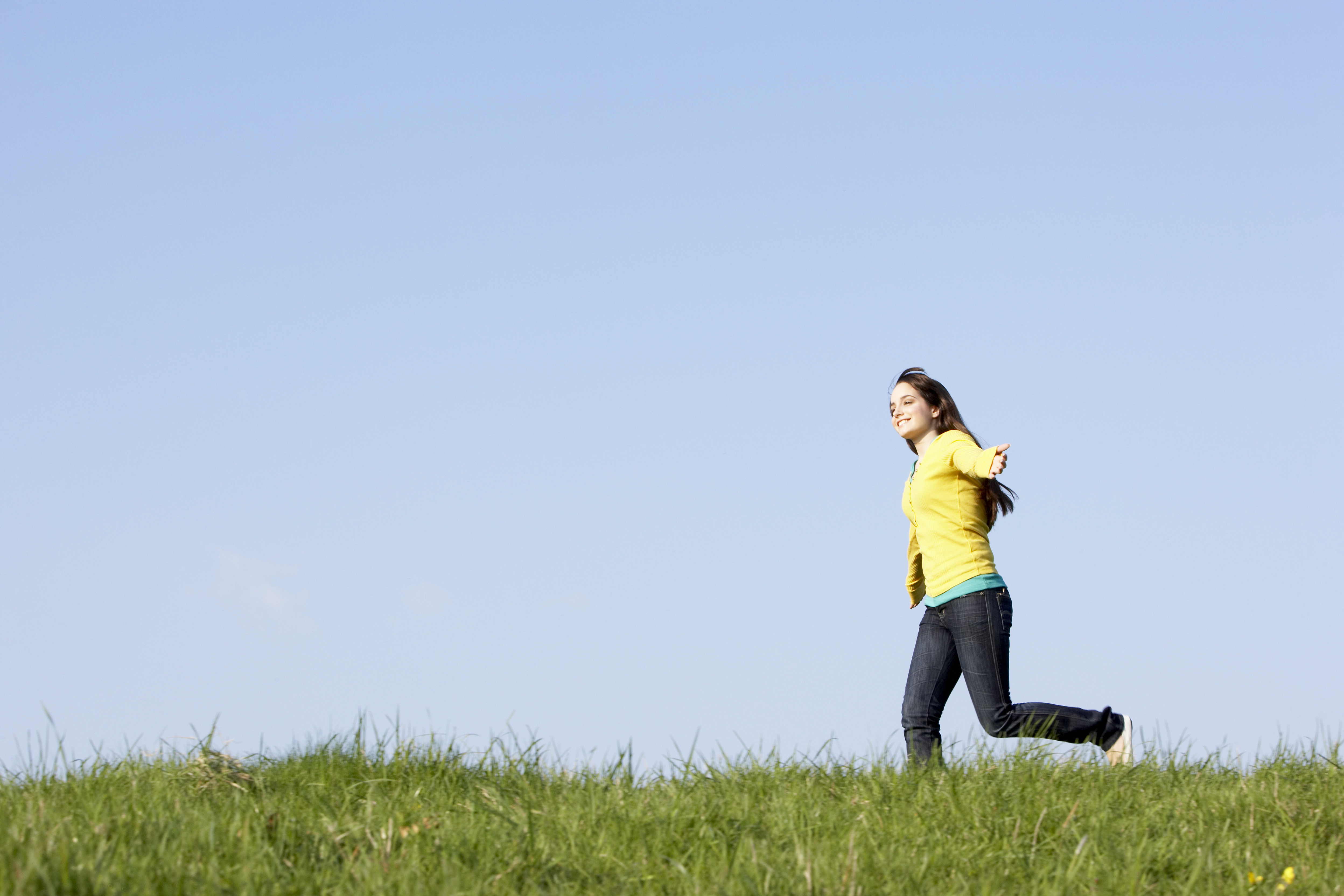 Adolescente corriendo por un prado en verano | Fuente: Shutterstock.com