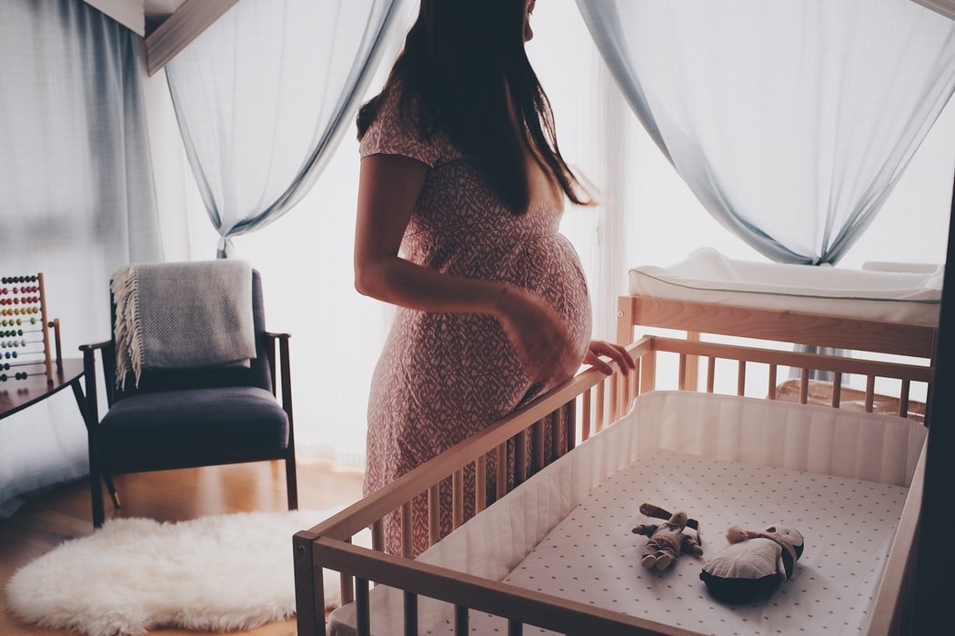Una mujer embarazada mirando su cuna. | Foto: Unsplash