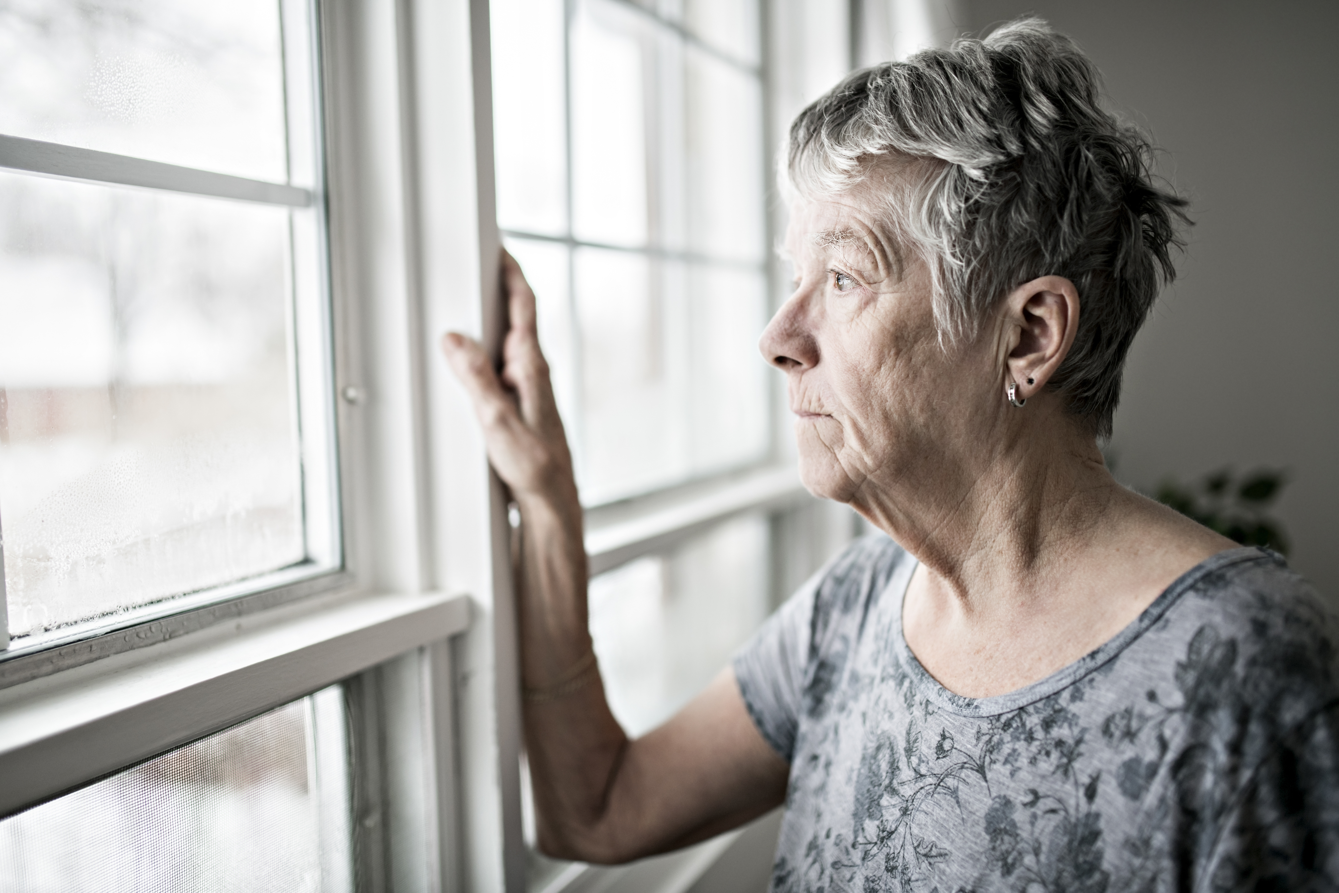 Mujer mayor disgustada mirando por una ventana | Foto: Getty Images