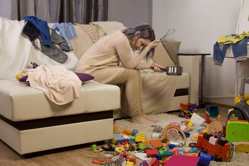 Madre cansada de ordenar la casa sentada en el sofá. Fuente: Shutterstock