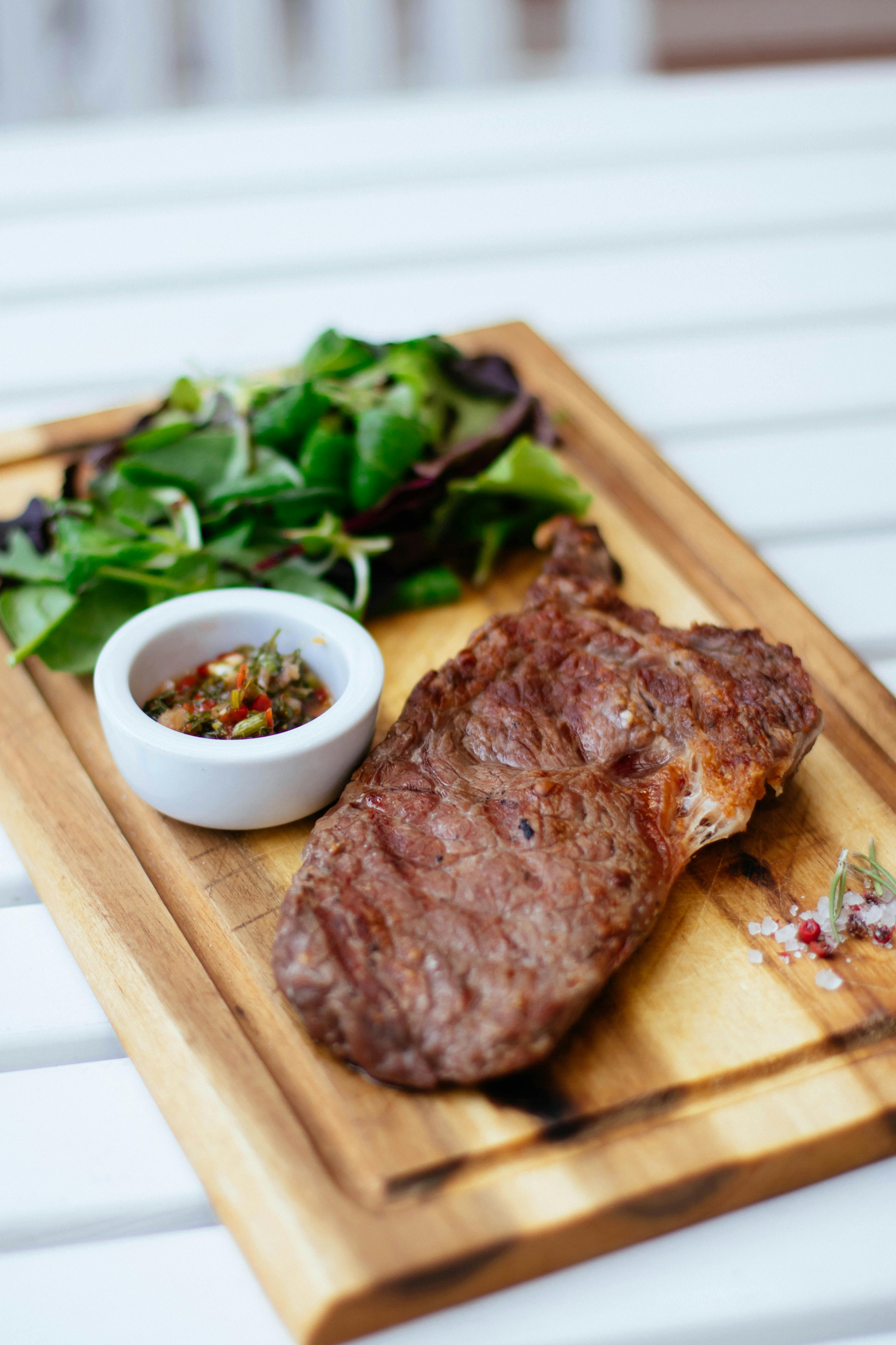 Una cena de bistec servida en una tabla de madera | Foto: Pexels