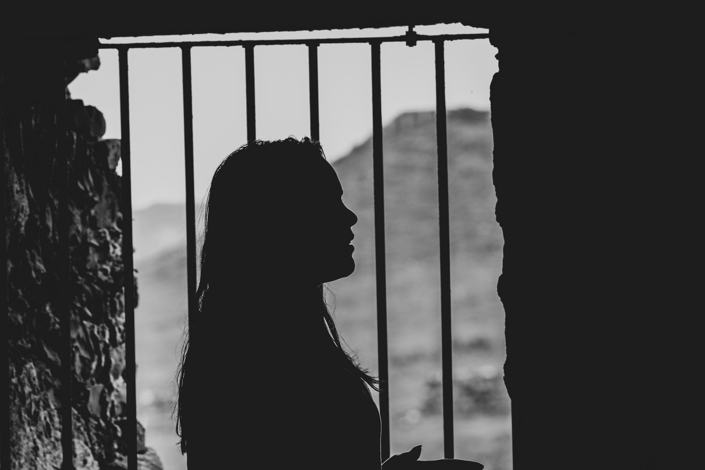 La silueta de una mujer junto a la ventana de la barra metálica | Fuente: Unsplash