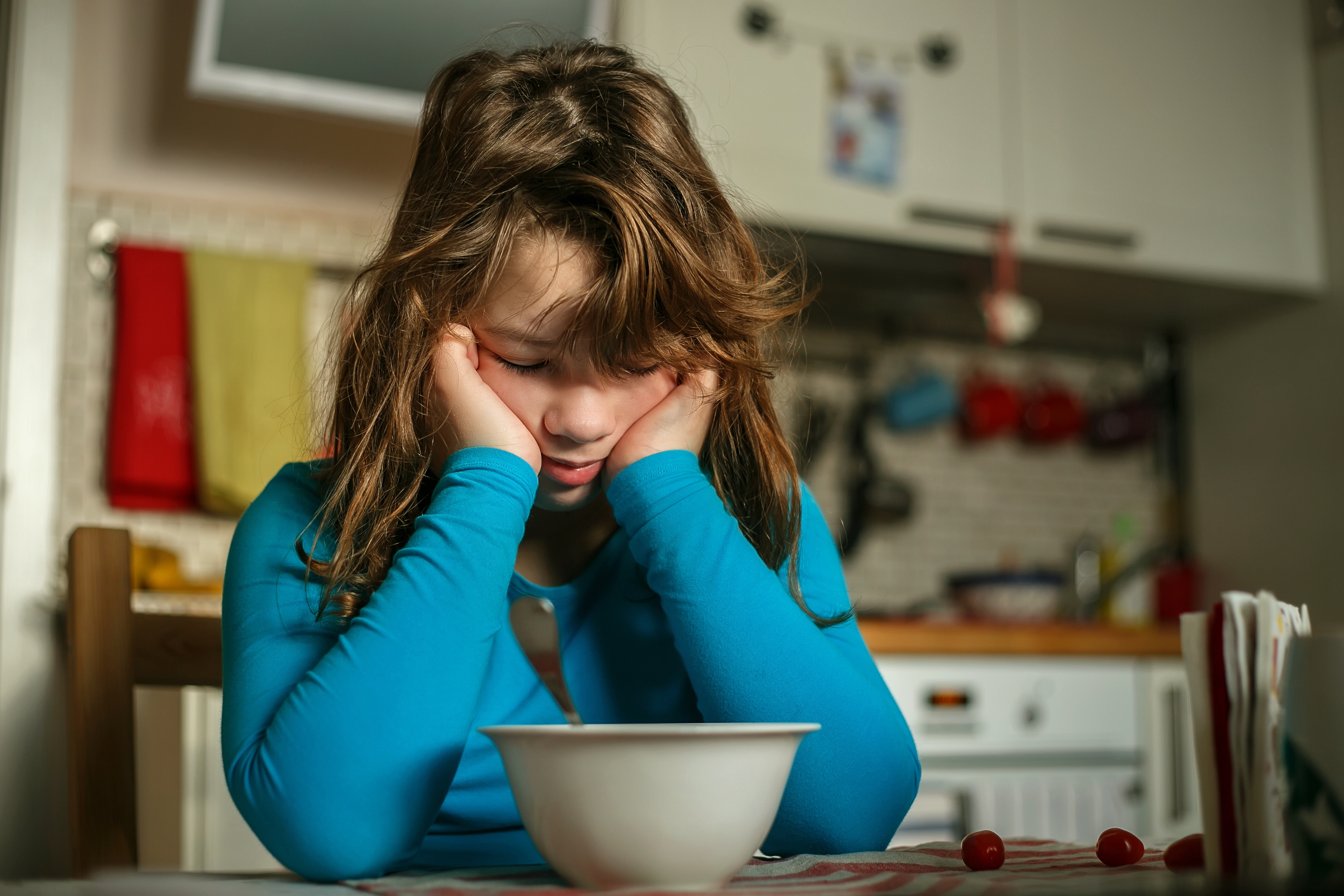 La chica inclinada sobre su plato de desayuno en pose contrariada | Fuente: Shutterstock.com
