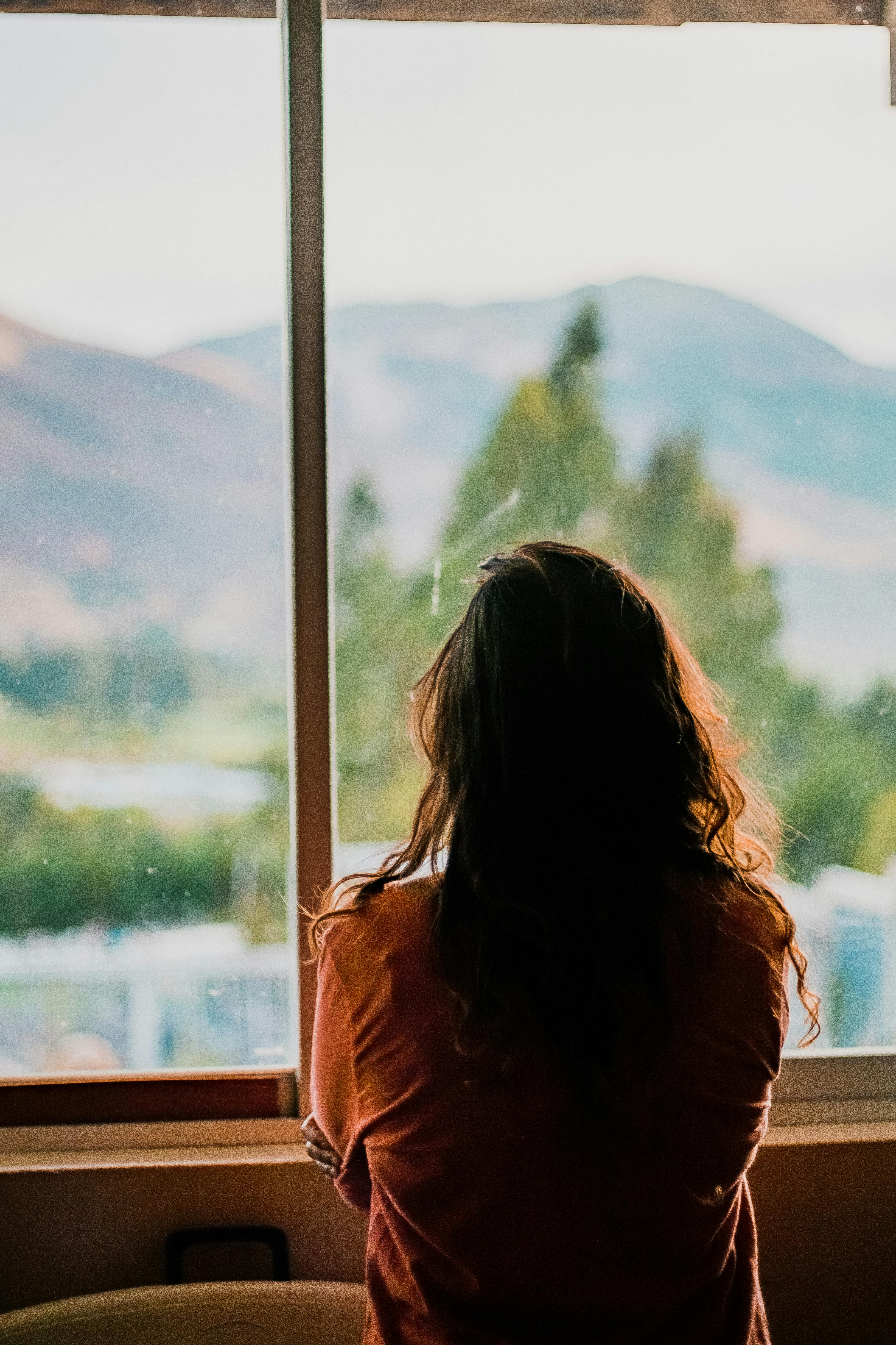 Una mujer mirando por la ventana | Fuente: Pexels