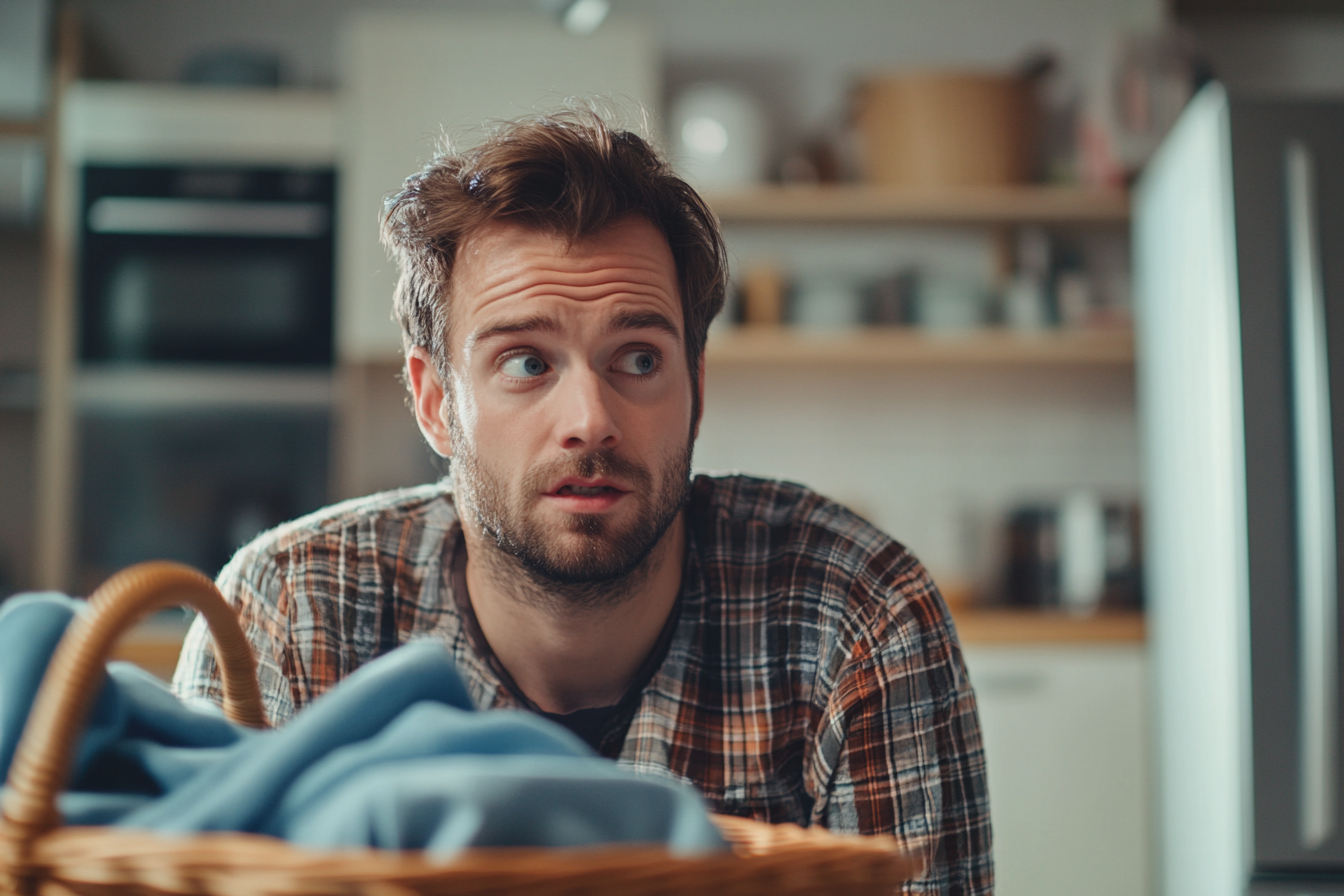 Un hombre ordenando la ropa sucia en su cocina | Fuente: Midjourney